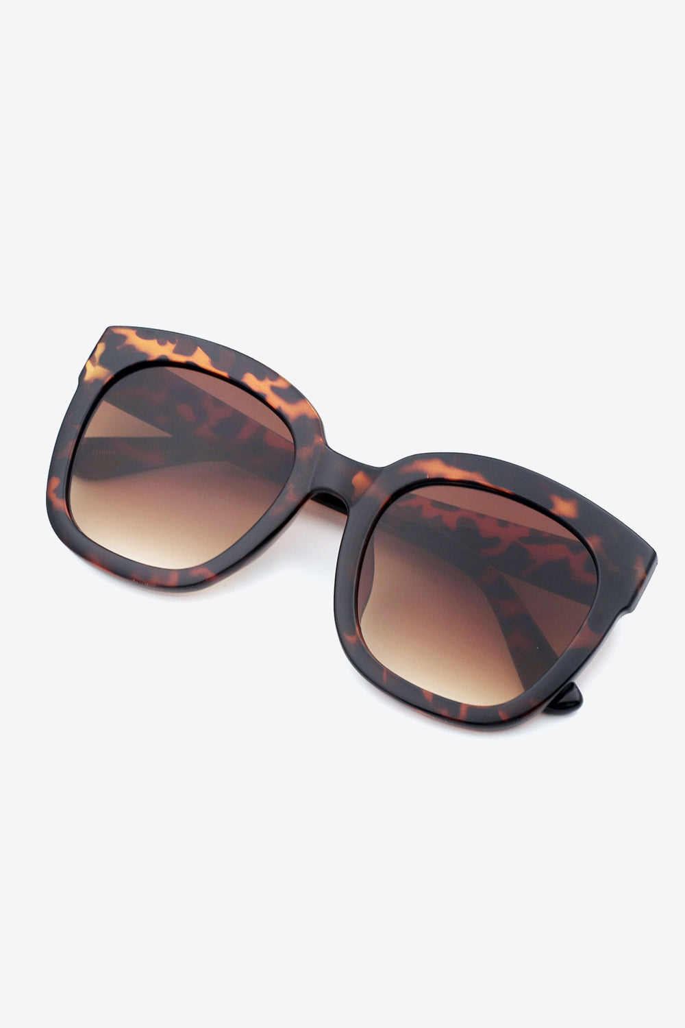 Tortoiseshell square sunglasses feature a substantial, softly rounded polycarbonate frame, matching temples, and brown gradient lenses for a polished statement look.