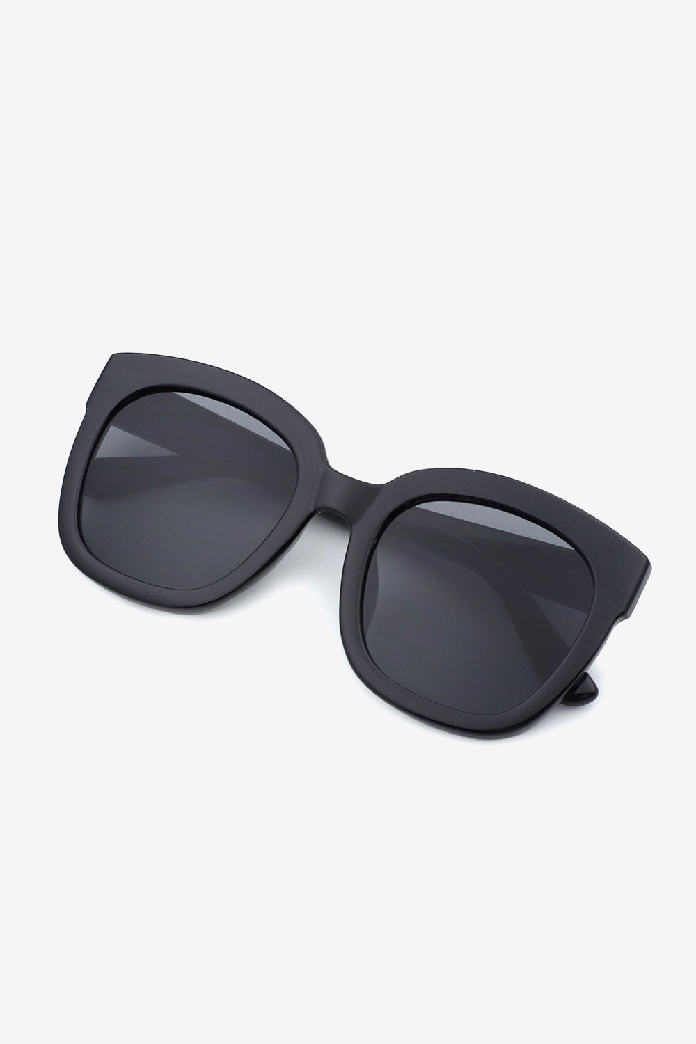Black polycarbonate frame square sunglasses feature a bold, softly rounded silhouette, substantial construction, dark acetate lenses, and matching temples.