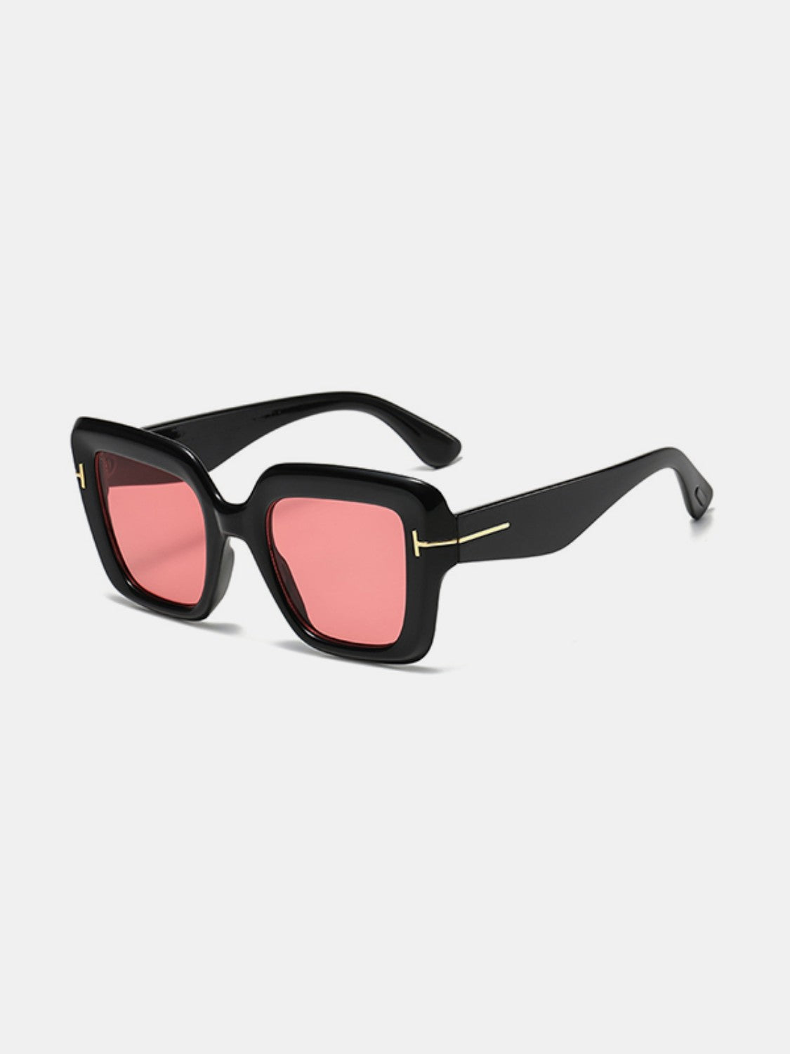 Black polycarbonate square sunglasses feature softly rounded frames, pink lenses, broad temples, and subtle gold-tone hinge accents.
