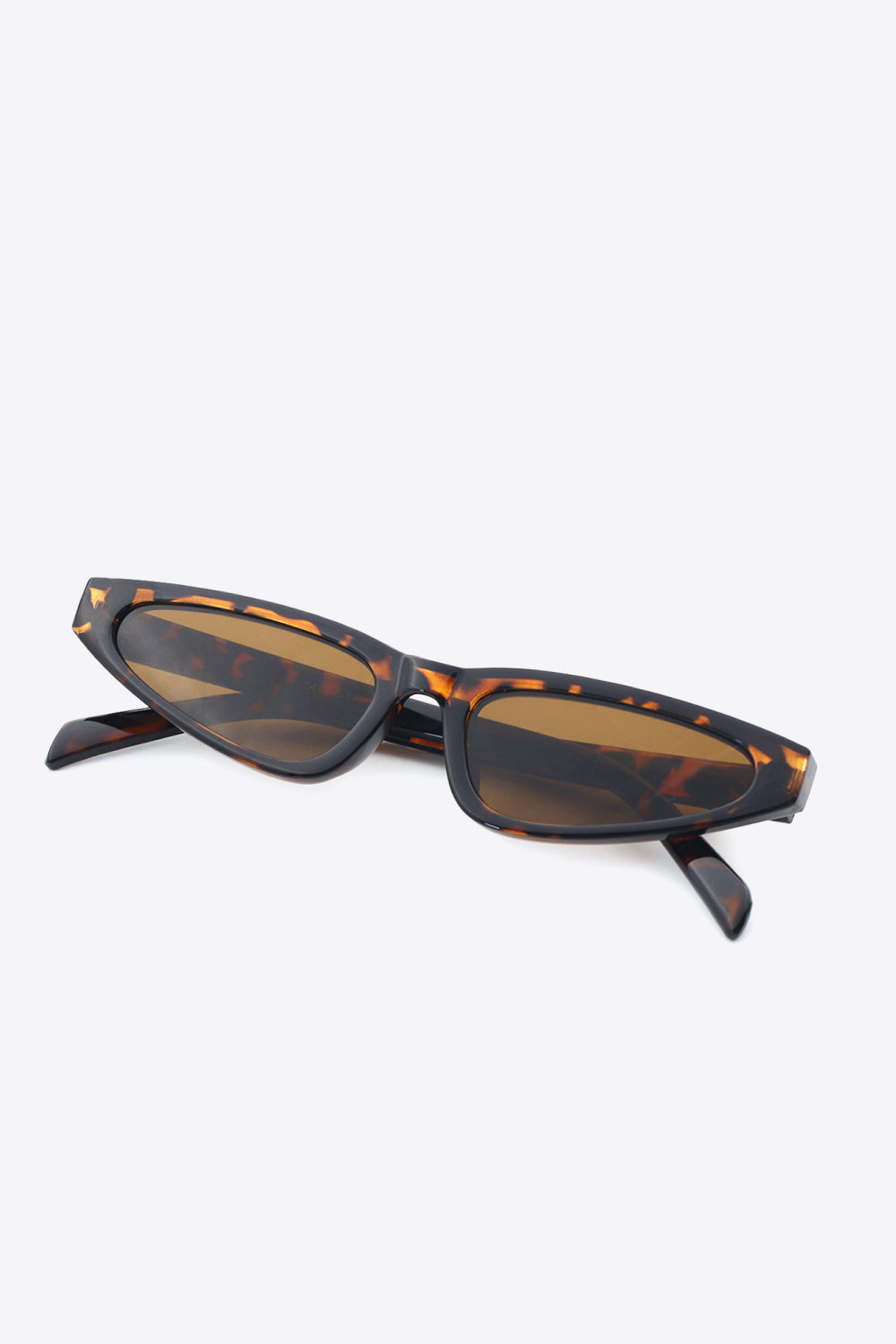 Tortoiseshell cat-eye sunglasses feature a gently upswept polycarbonate frame, dark temples, and warm brown acetate lenses for a retro-inspired silhouette.