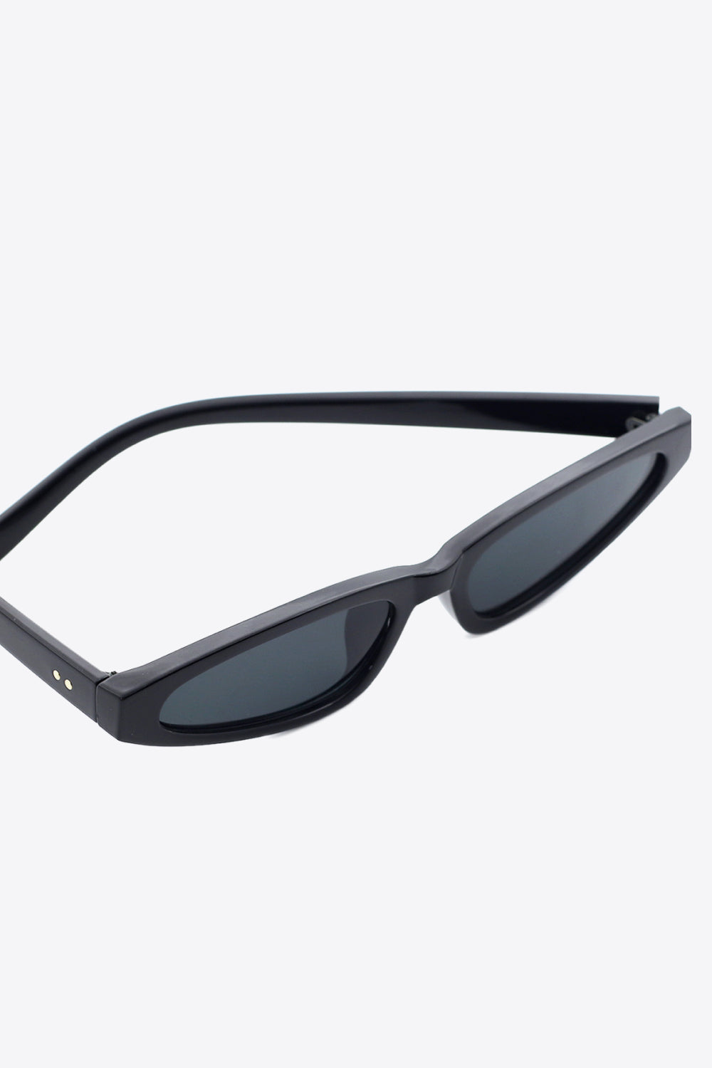 Black polycarbonate cat-eye sunglasses feature a sleek, gently upswept frame, dark acetate lenses, and matching structured temples.