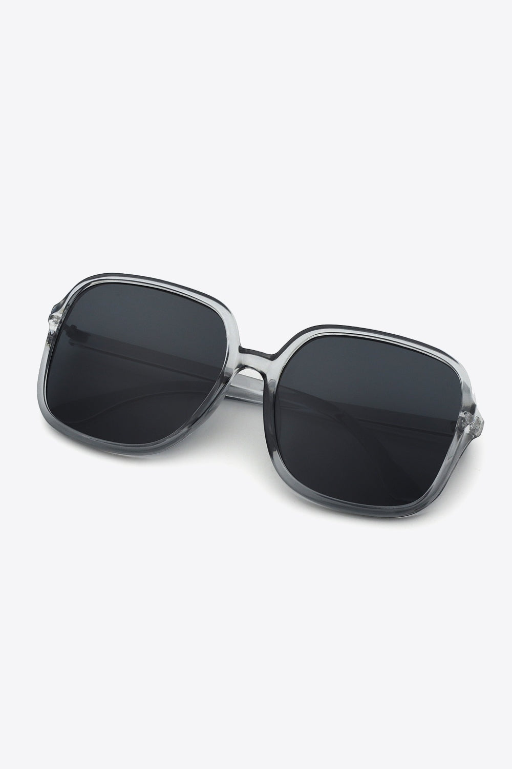 Square polycarbonate sunglasses with a softly rounded, transparent gray frame, broad dark lenses, a defined top line, and sleek matching temples.