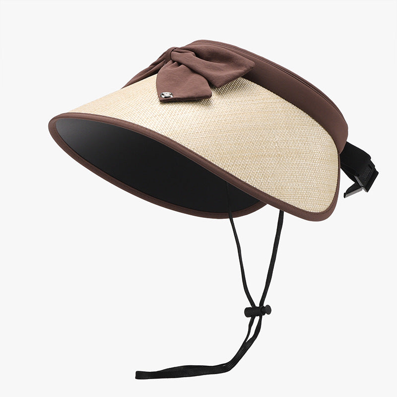 Natural grass and polyester adjustable sun hat with a curved visor, generous brown-trimmed brim, softly gathered bow, open back, rear fastening, and chin cord.
