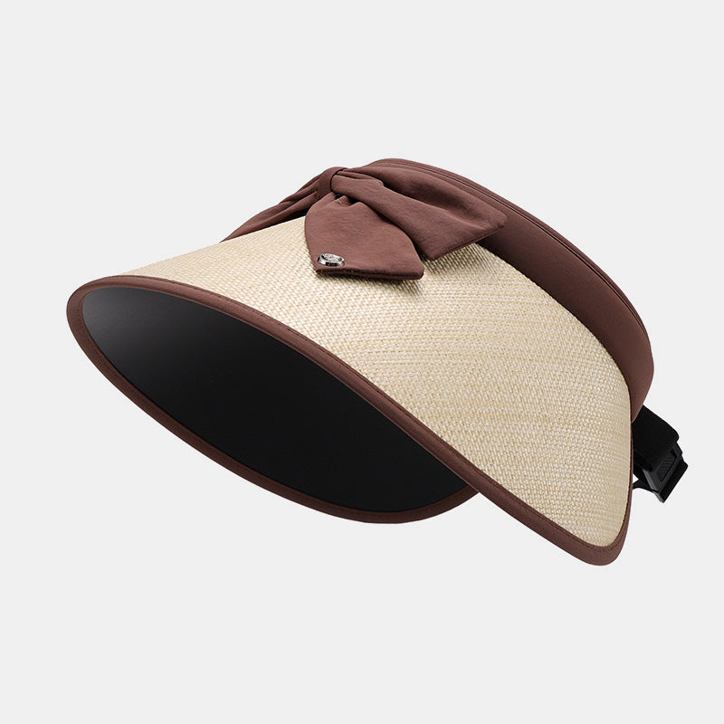 Woven polyester sun hat with a curved visor, generous cream brim, brown trim, gathered bow accent, and adjustable open-back fastening.