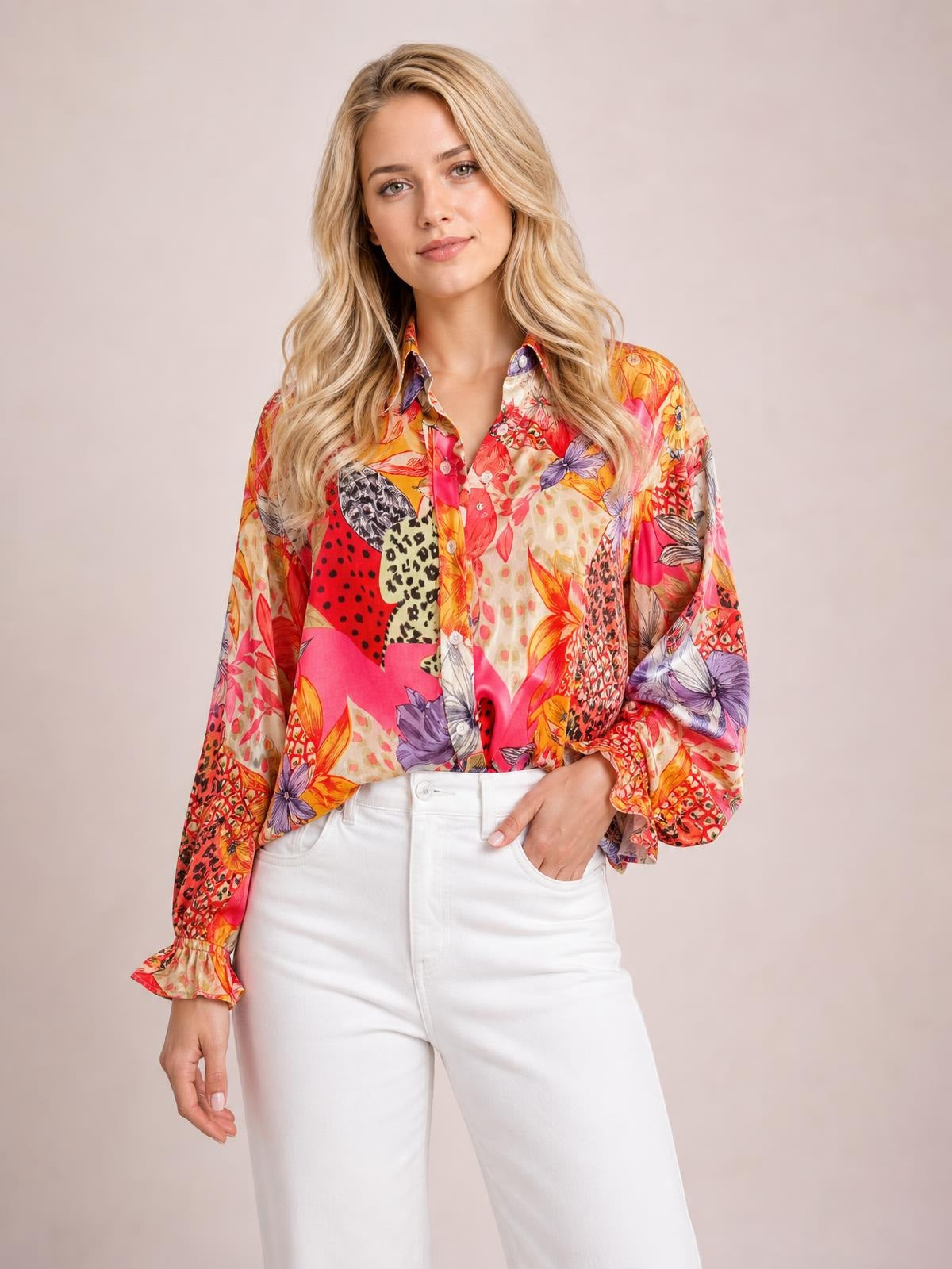 Model poses with one hand in her pocket wearing a colorful printed button-down long-sleeve shirt with a relaxed silhouette, collar, and front buttons.