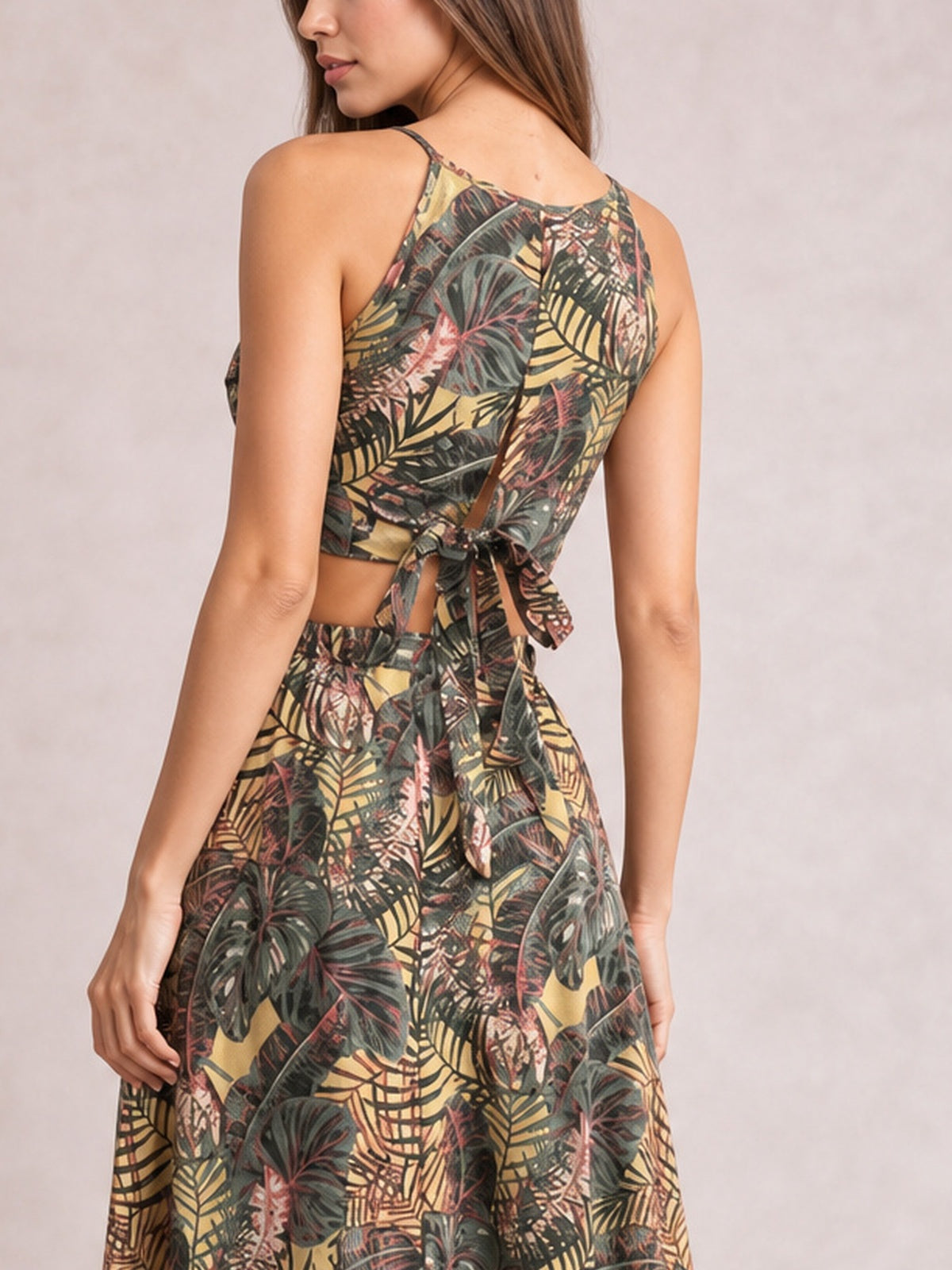 A model stands turned away in a tropical-print cami and high-waisted slit skirt set, featuring slender straps, a cropped fit, tied back, and flowing midi silhouette.