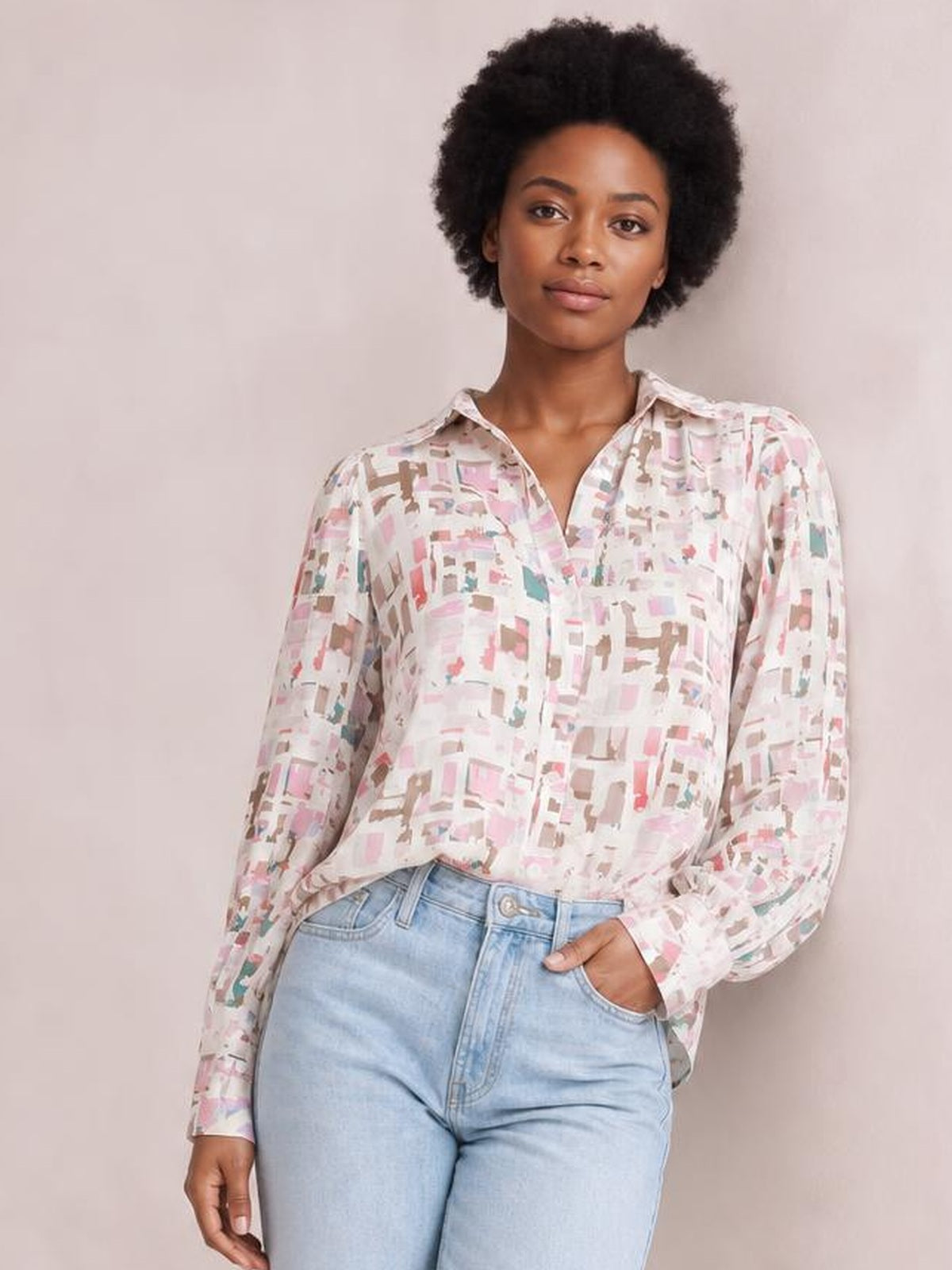 Model wearing a pastel abstract printed collared neck long sleeve shirt with a relaxed silhouette, button-front construction, and one hand tucked into her jeans pocket.
