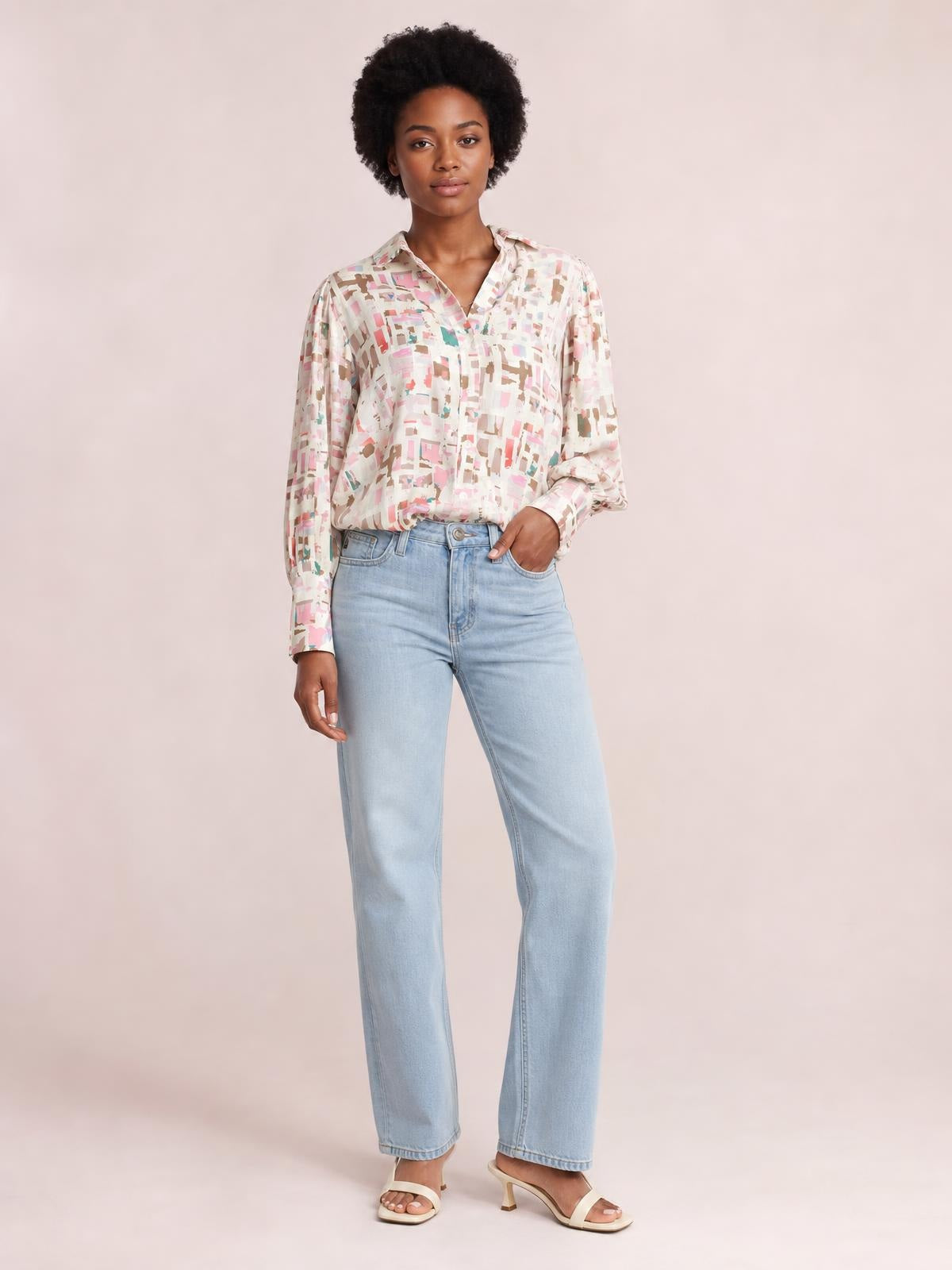 Model poses with one hand in her pocket wearing a pastel printed collared neck long sleeve shirt with a relaxed silhouette and button-front construction.