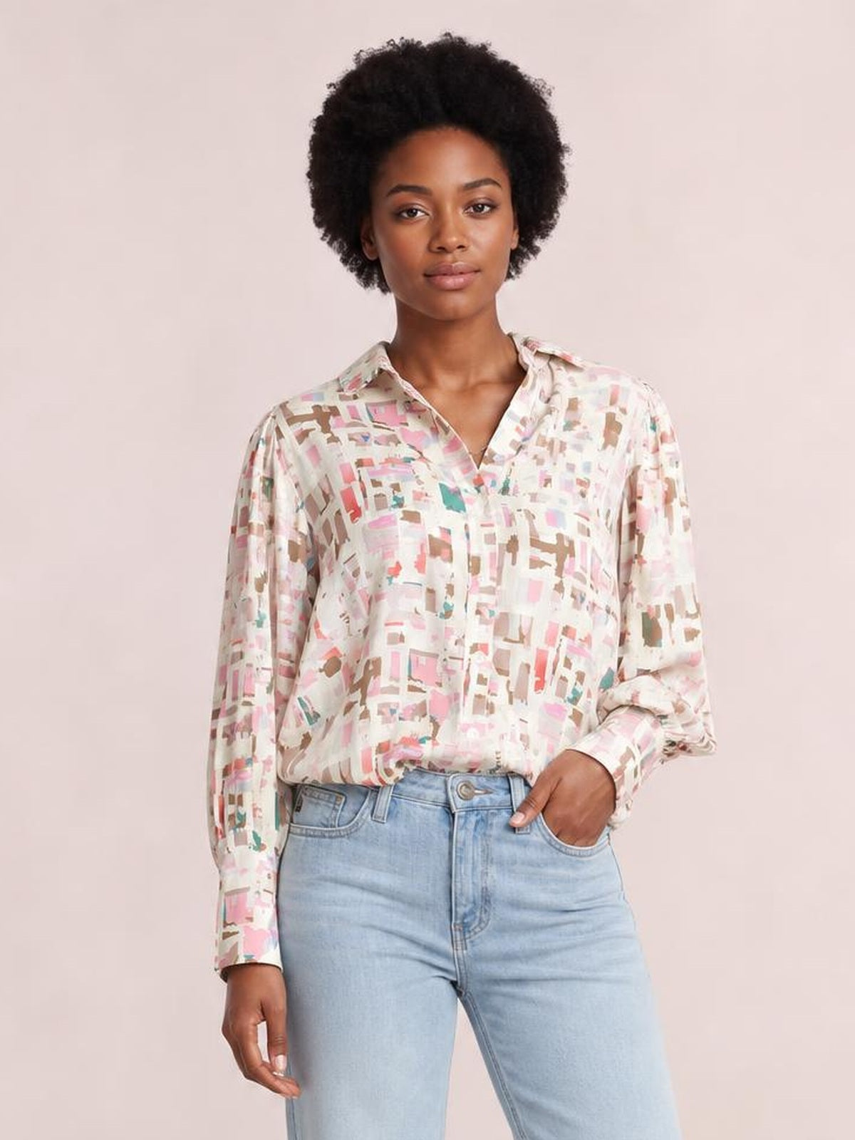 Model wearing an opaque pastel printed collared neck long sleeve shirt with a relaxed silhouette, button front, and one hand in her jeans pocket.
