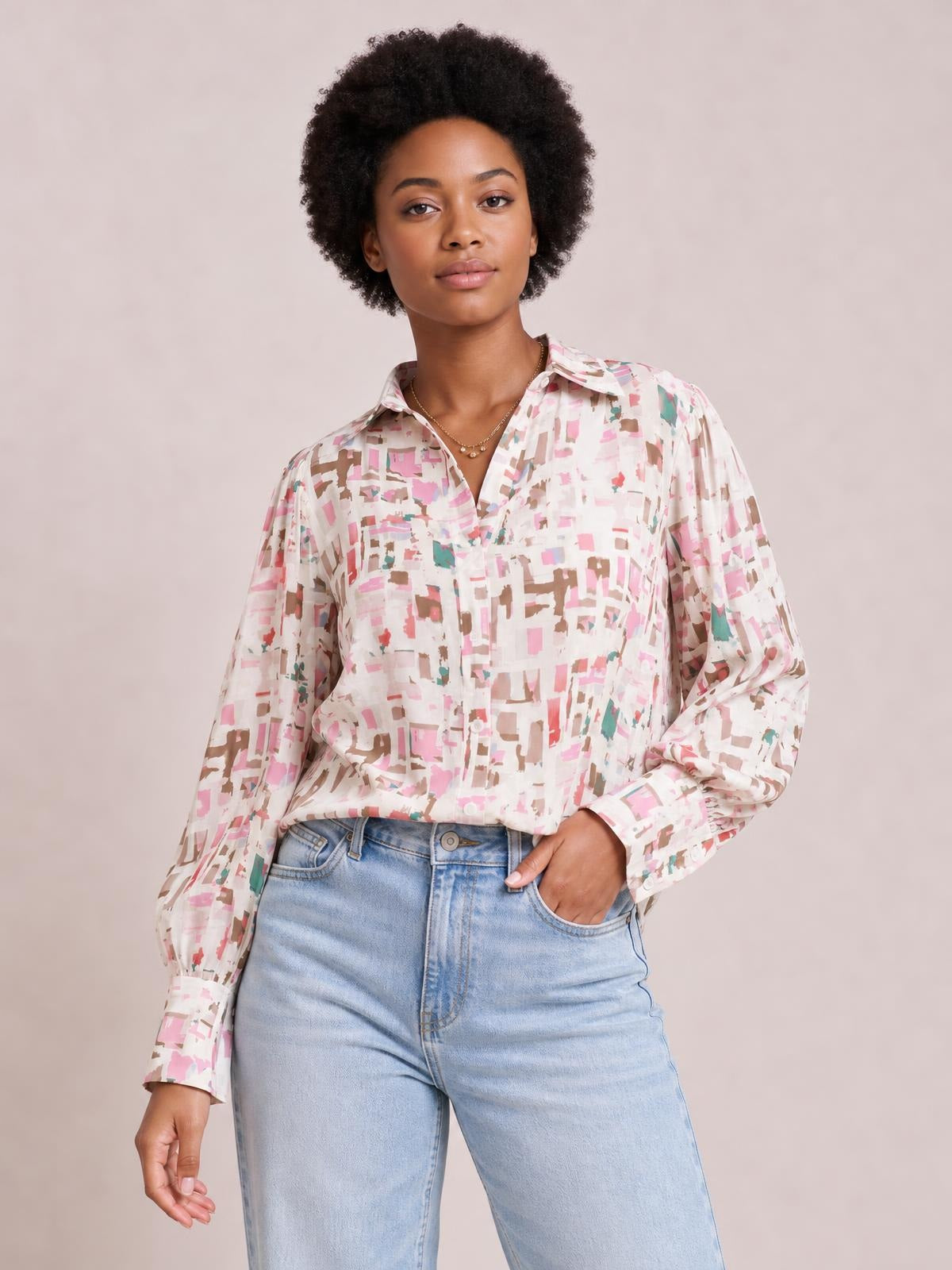 A model wears a pastel abstract printed collared long-sleeve shirt with a button-front placket and relaxed silhouette, standing with one hand in her jeans pocket.