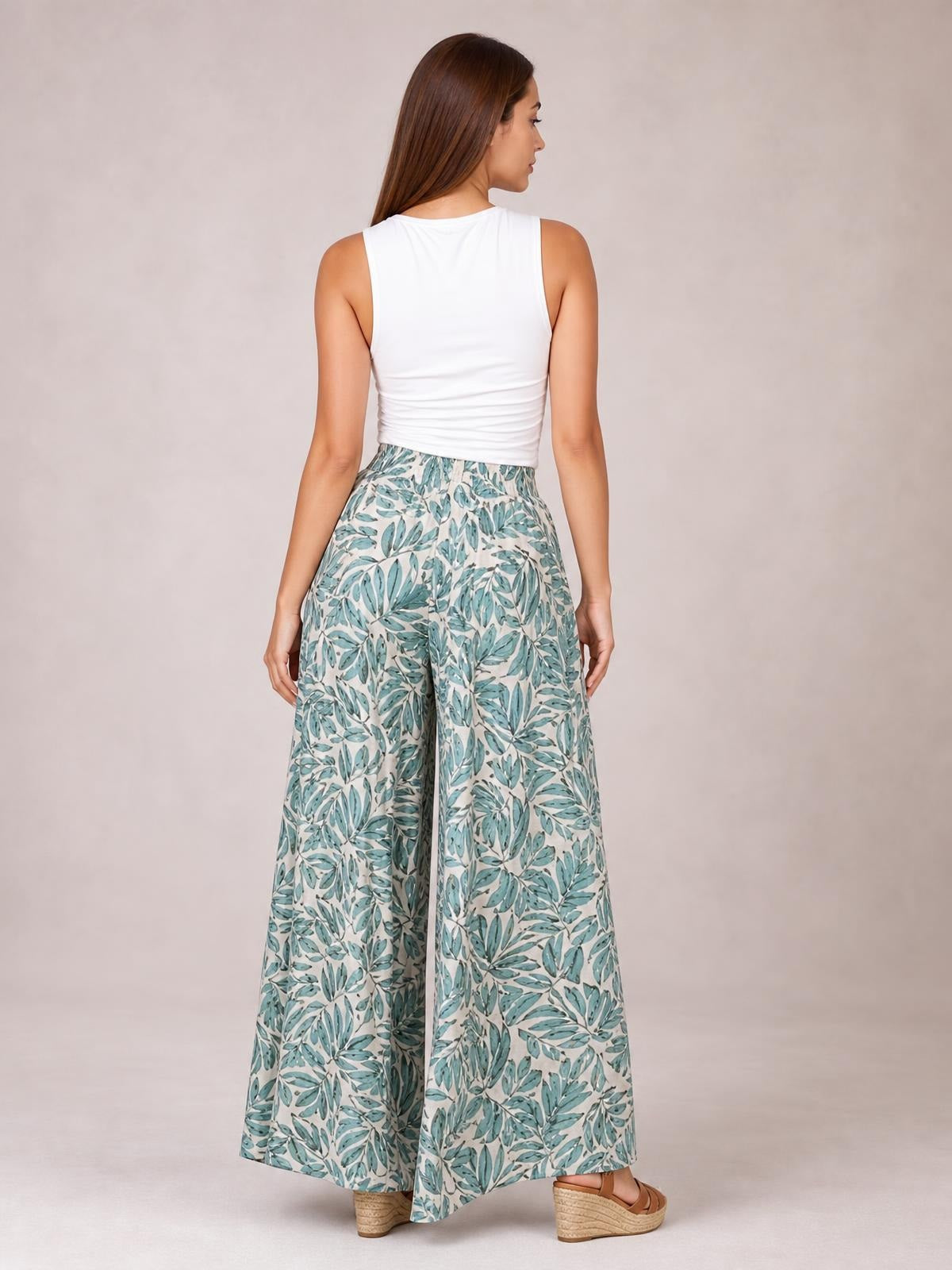 Model shown from the back wearing printed high waist wide leg pants in a teal leaf pattern with a flowing full-length silhouette.