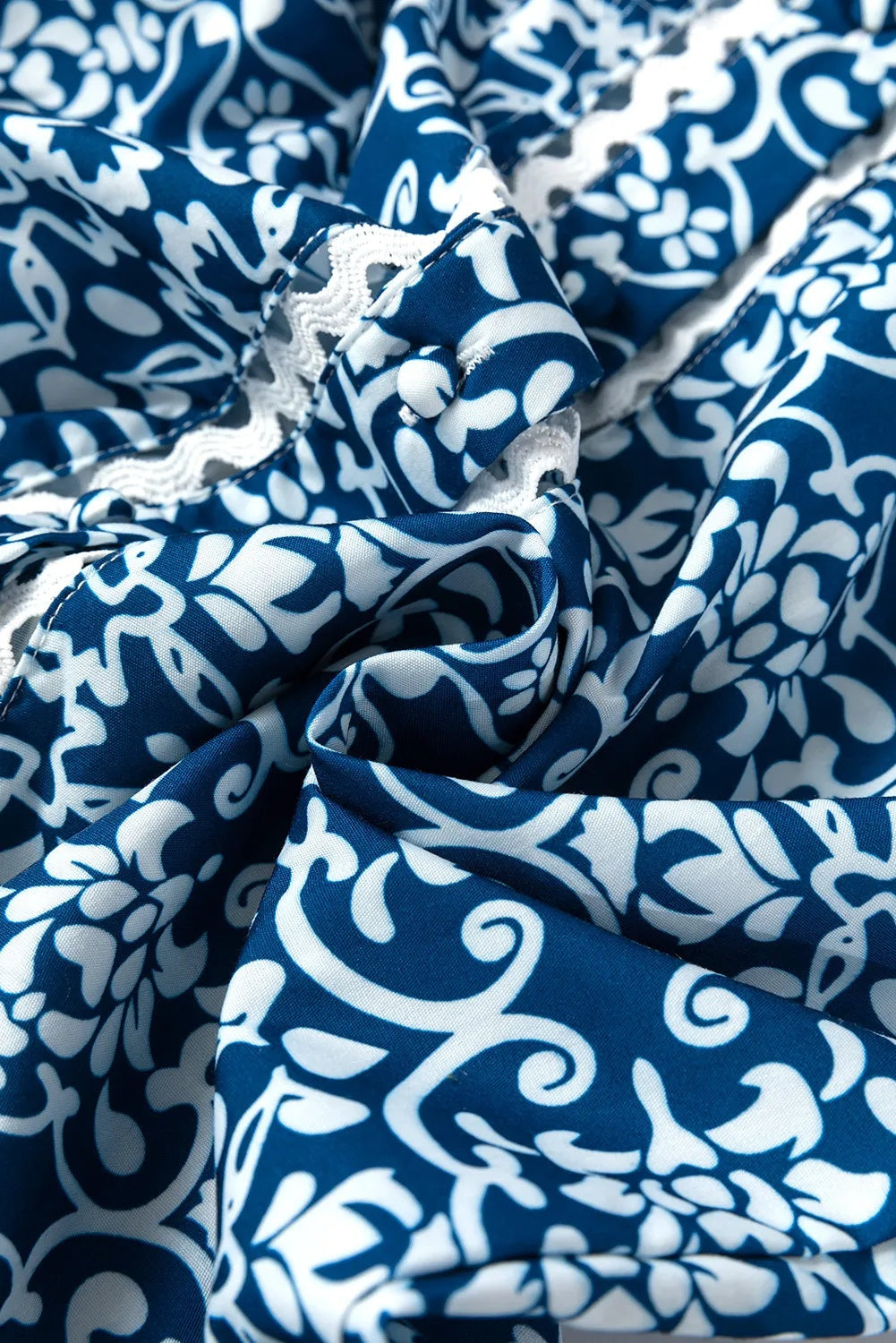 Blue-and-white printed blouse fabric shown in close-up, with flowing folds and a visible stitched edge highlighting the garment’s lightweight construction.