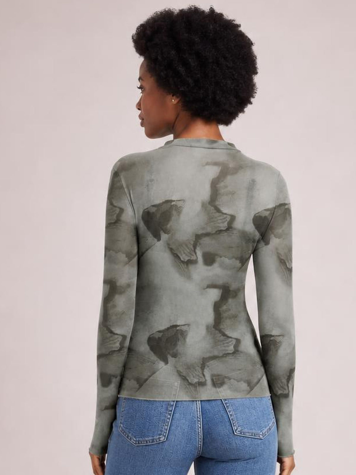 Model shown from the back wearing a fitted gray printed mock neck long sleeve mesh T-shirt with a sheer, stretch silhouette.