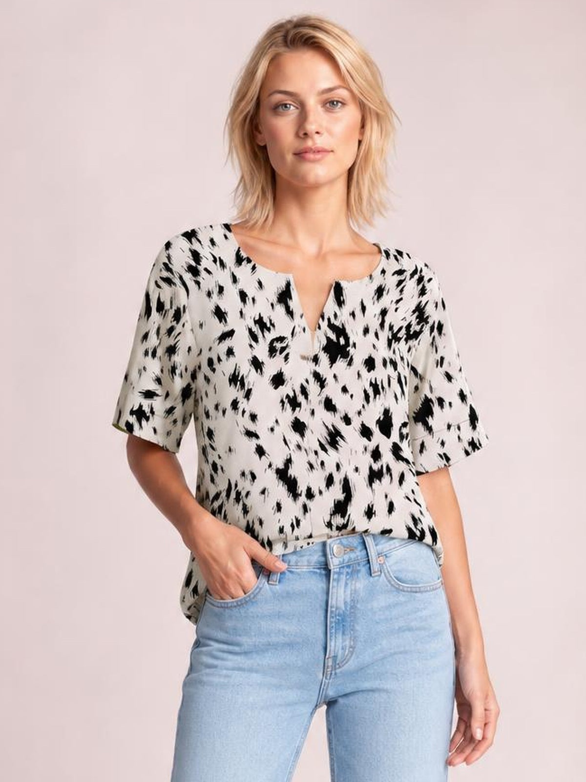 Model wearing a black-and-white printed blouse with a notched neck, regular half sleeves, and a relaxed regular-length silhouette, posing with one hand in her jeans pocket.