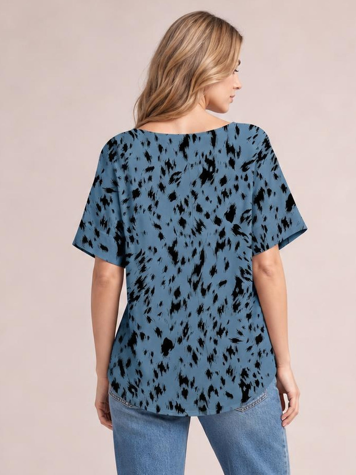 Model stands facing away in a relaxed blue printed blouse with black abstract pattern, loose silhouette, regular length, and short half sleeves.