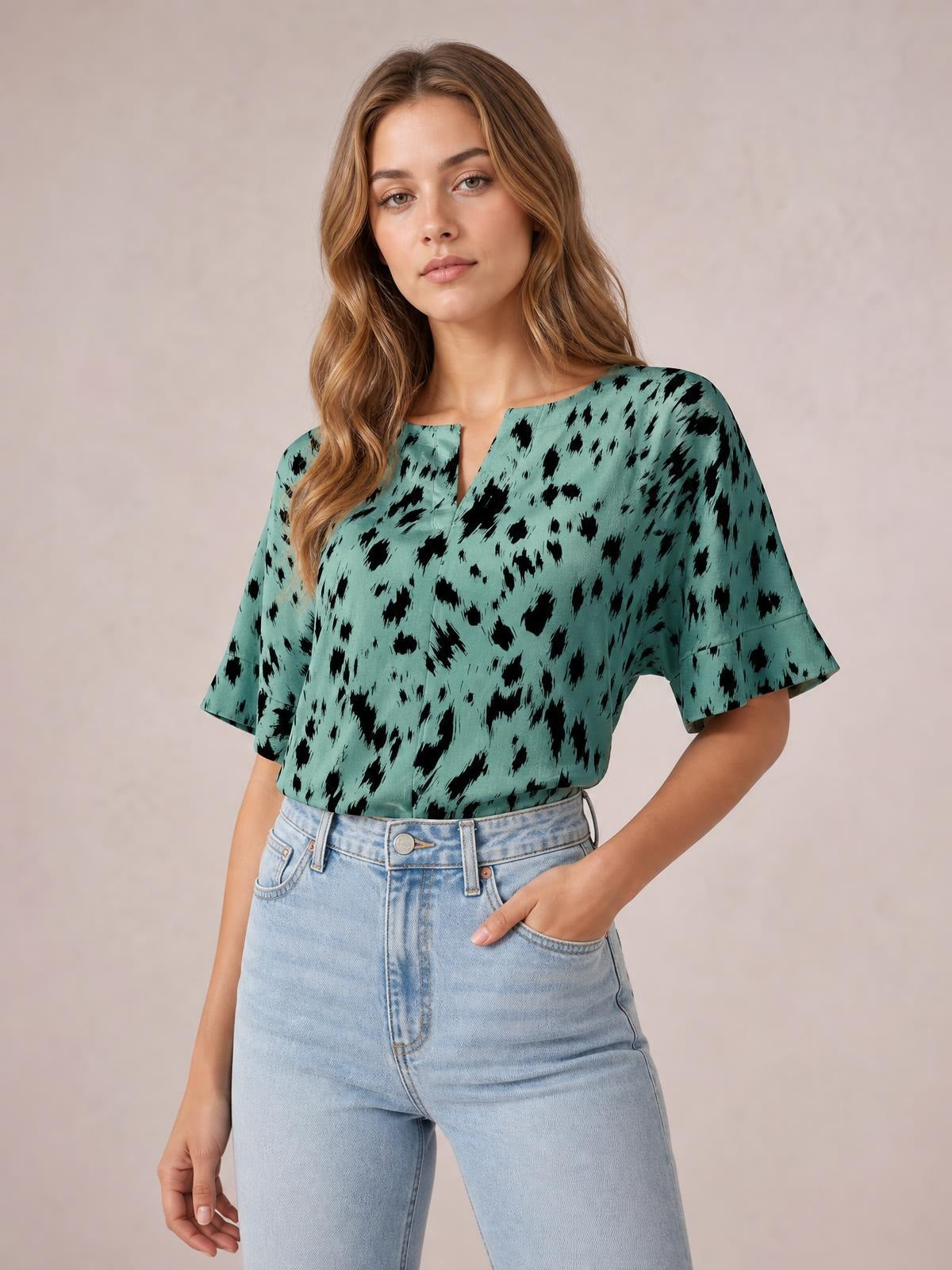 Model wearing a turquoise printed blouse with black abstract spots, a notched neckline, regular half sleeves, and a relaxed regular-length silhouette.