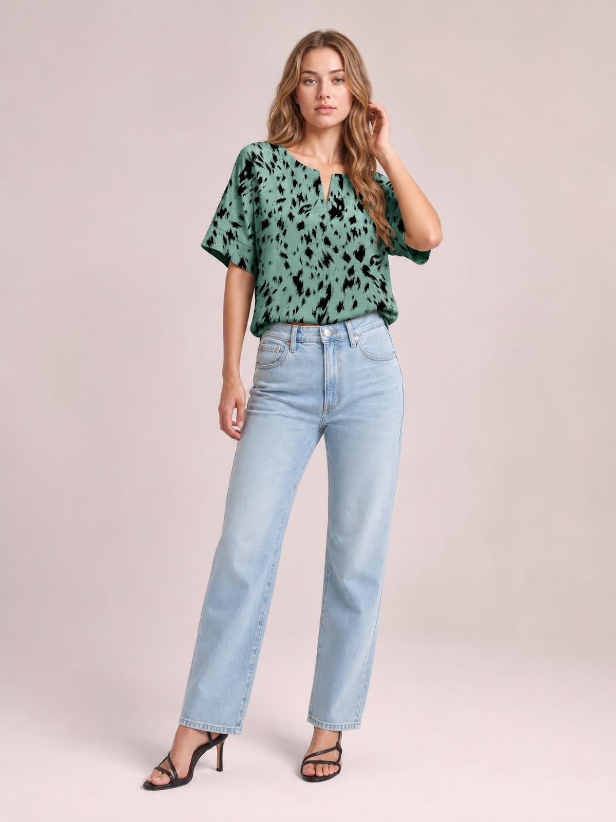 Model wearing a mint green printed blouse with a notched neck, relaxed regular silhouette, and short half sleeves, posing with one hand near her hair.