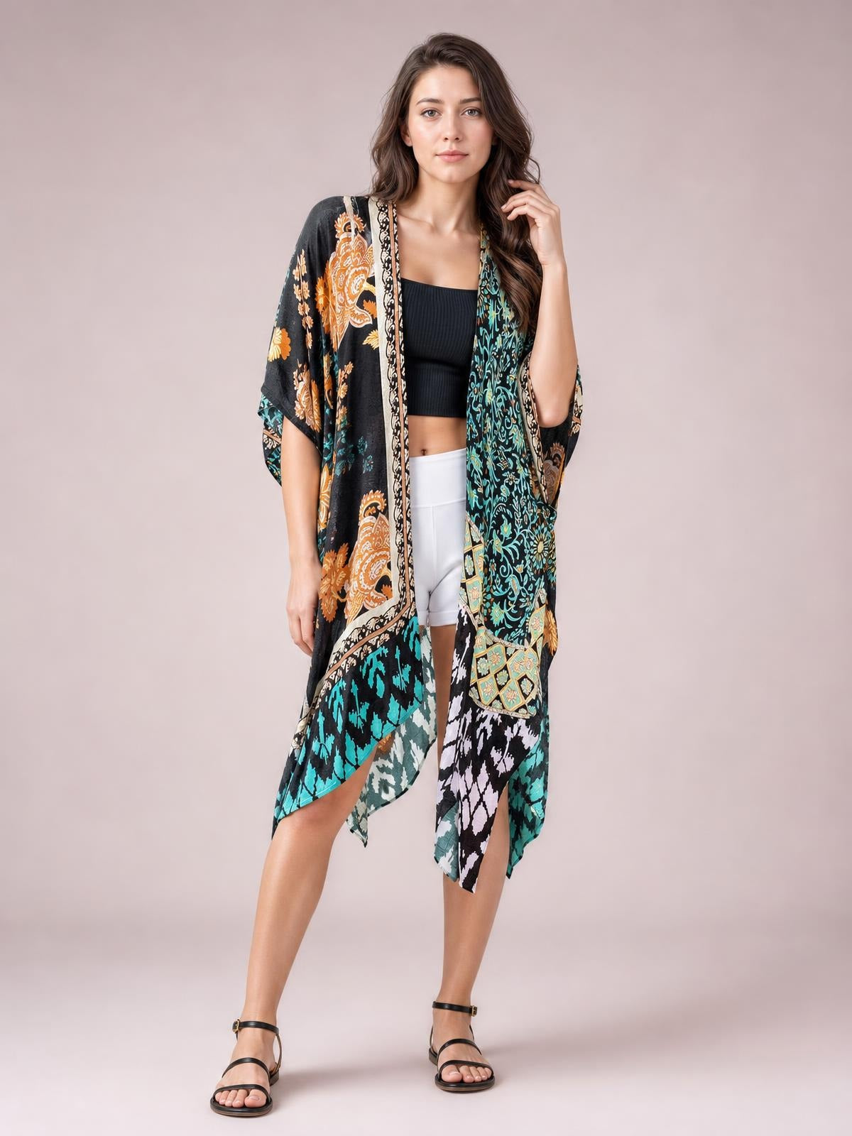 Model poses in a colorful printed open-front cover-up with a black base, flowing long silhouette, wide sleeves, and contrasting border details.
