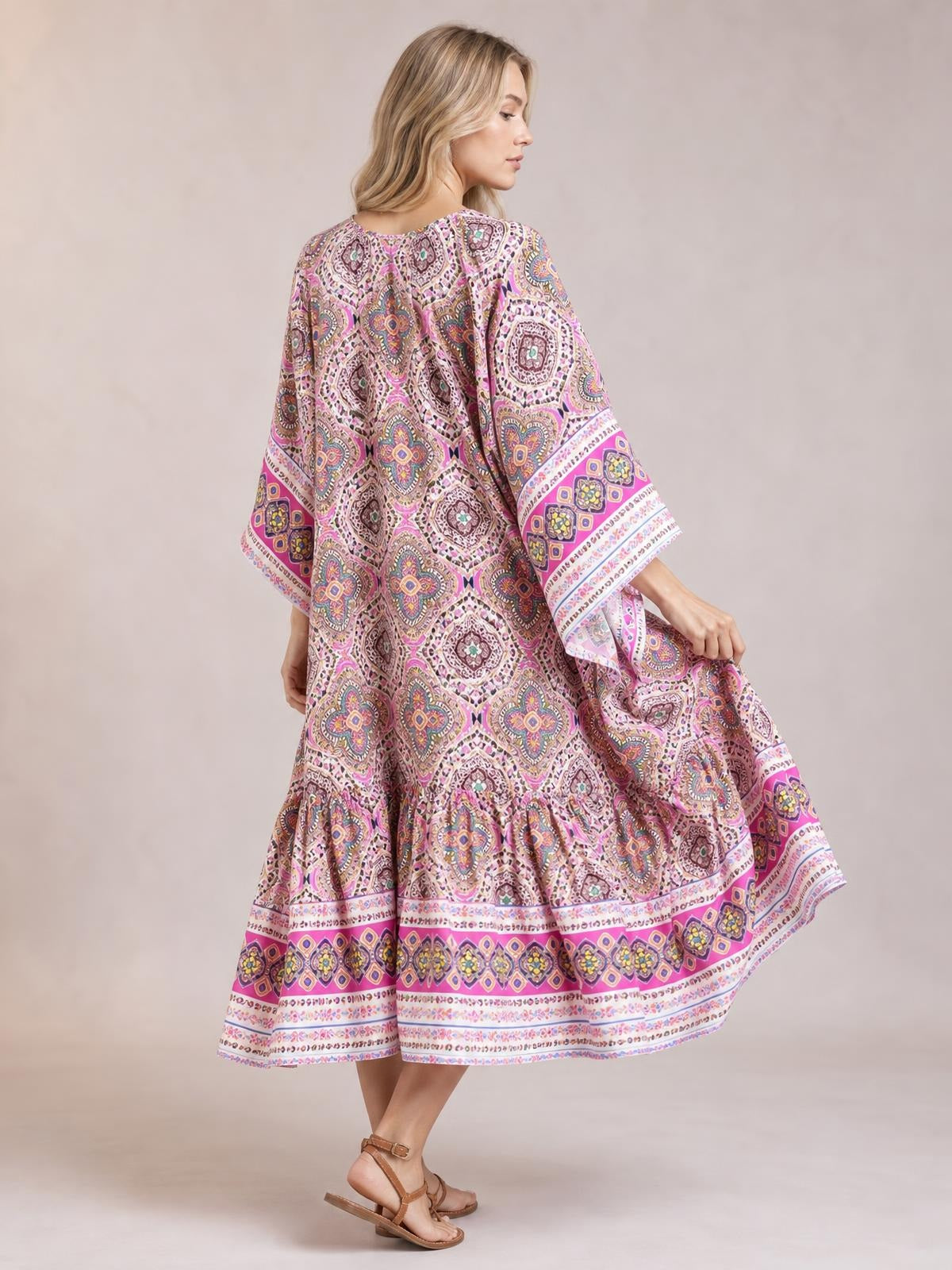 A model poses in a flowing printed open front cover up with wide sleeves, colorful pink and purple geometric motifs, border trim, and a relaxed silhouette.
