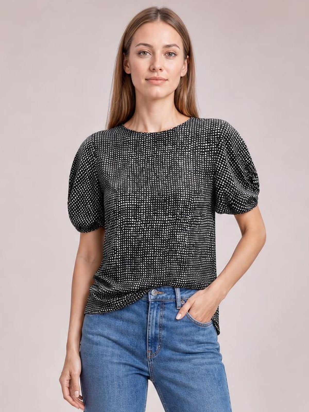Model wearing a black printed round-neck short-sleeve blouse with a relaxed straight silhouette and gently gathered sleeves, posed with one hand in her jeans pocket.