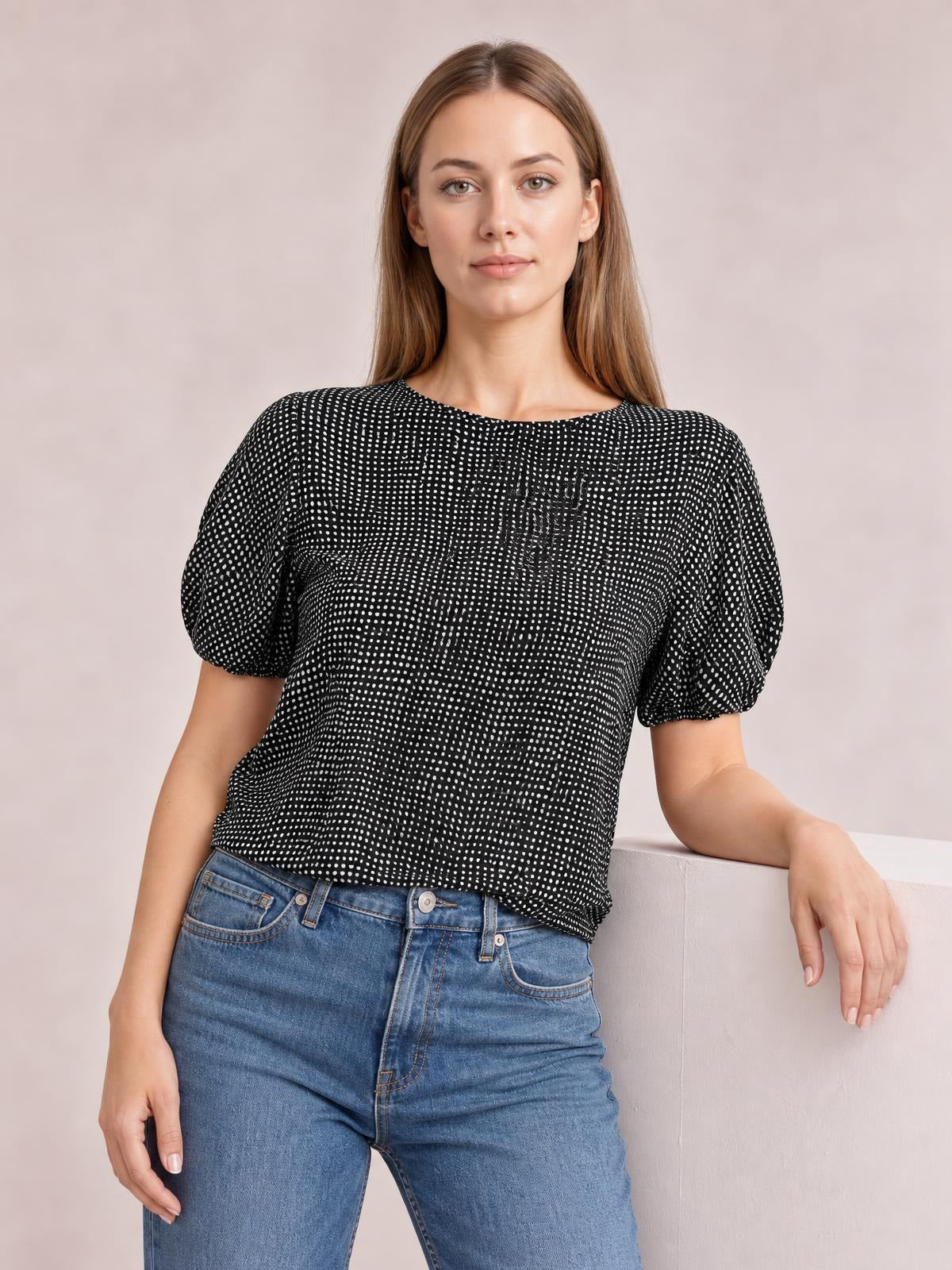 Model wearing a black printed round neck short sleeve blouse with puffed sleeves, a relaxed straight silhouette, and a gently curved hem.