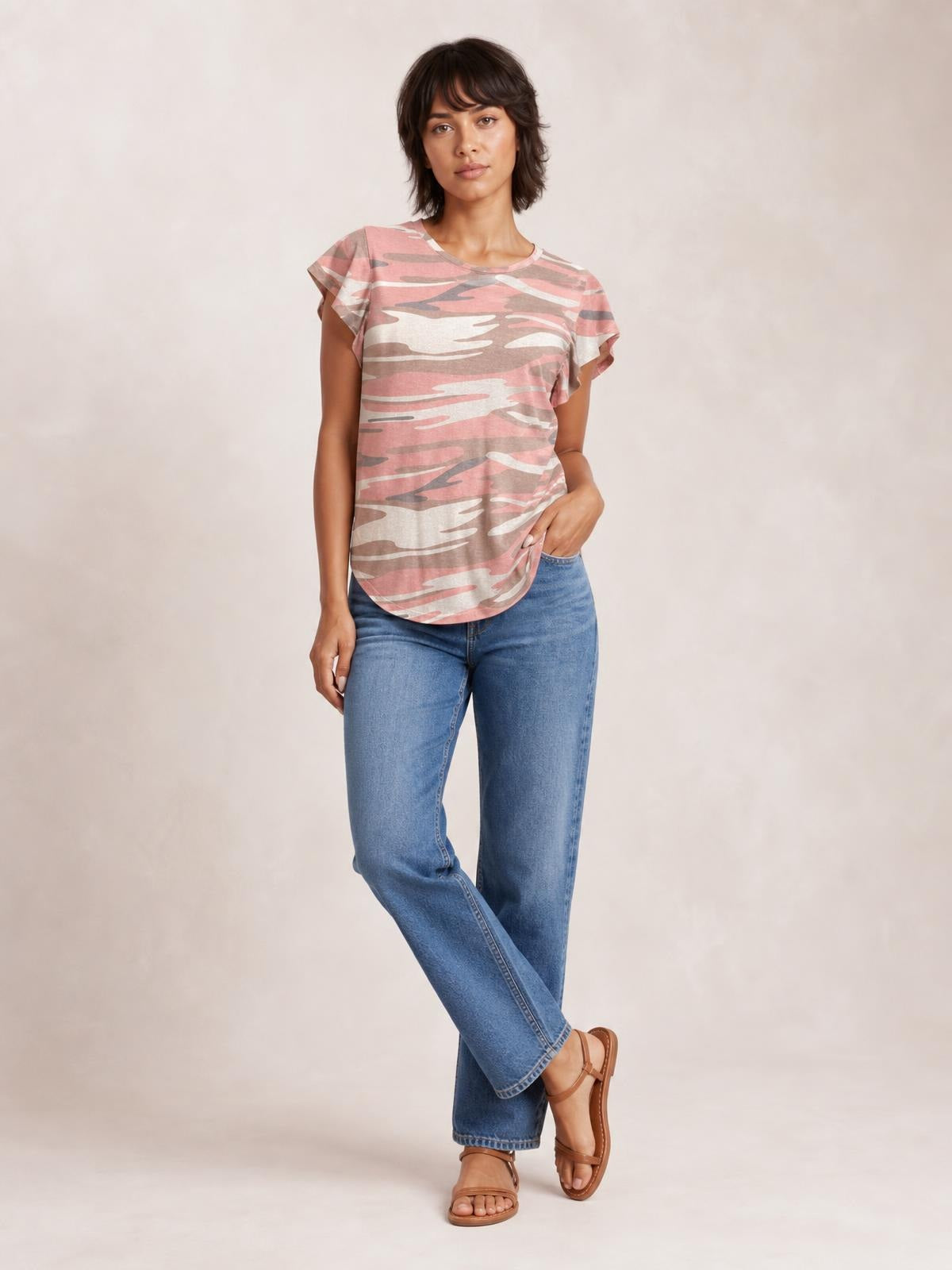 Model poses in a pink and gray camouflage-print round-neck short-sleeve T-shirt with a relaxed silhouette and curved hem.