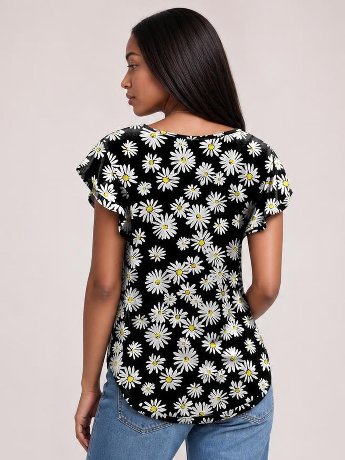 A woman models a black printed round-neck short-sleeve T-shirt with white daisies, a relaxed silhouette, and a curved hem, viewed from behind.