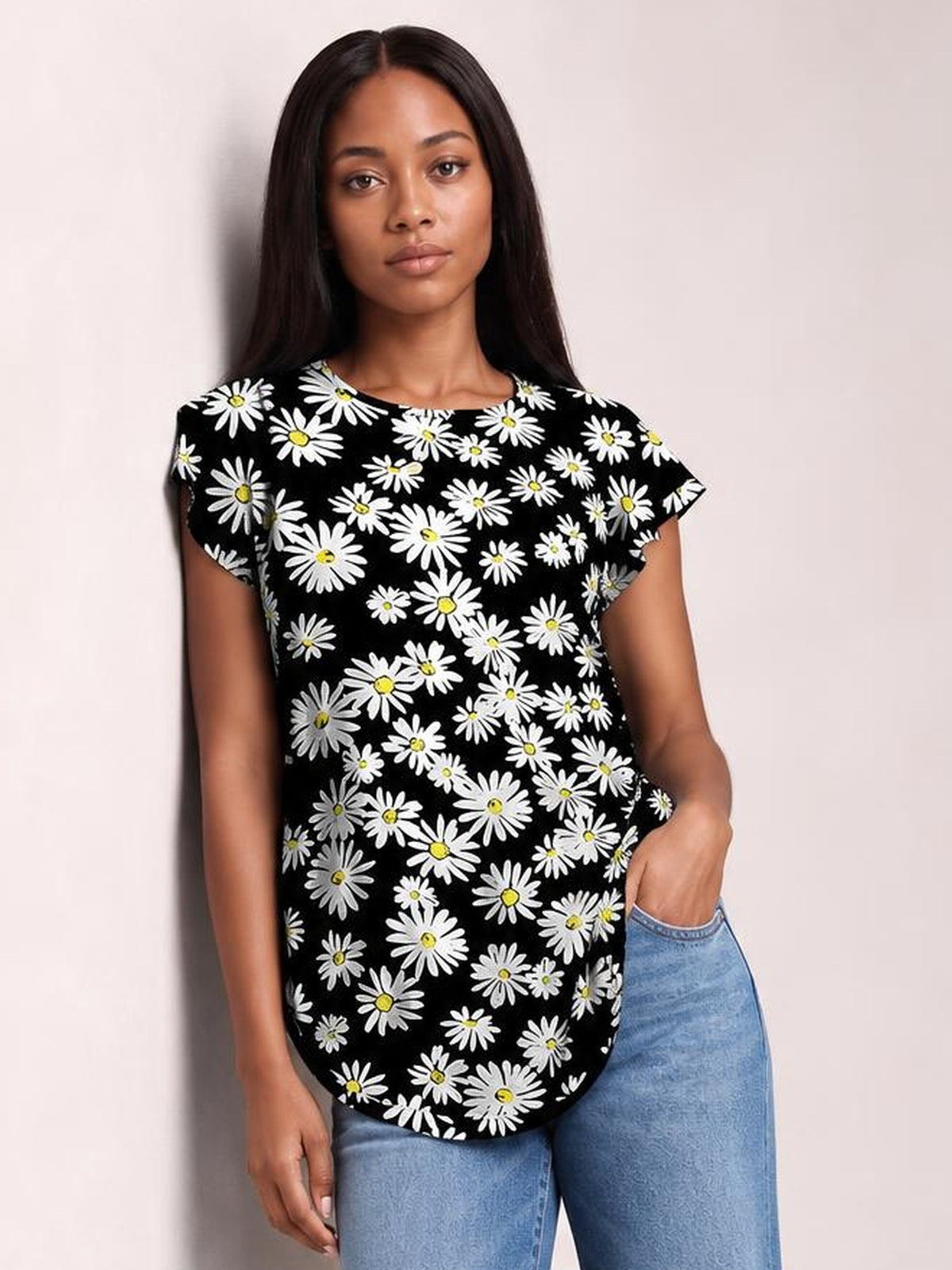 A model wears a black printed round neck short sleeve T-shirt with white daisy flowers, a relaxed silhouette, and a curved hem over light blue jeans.