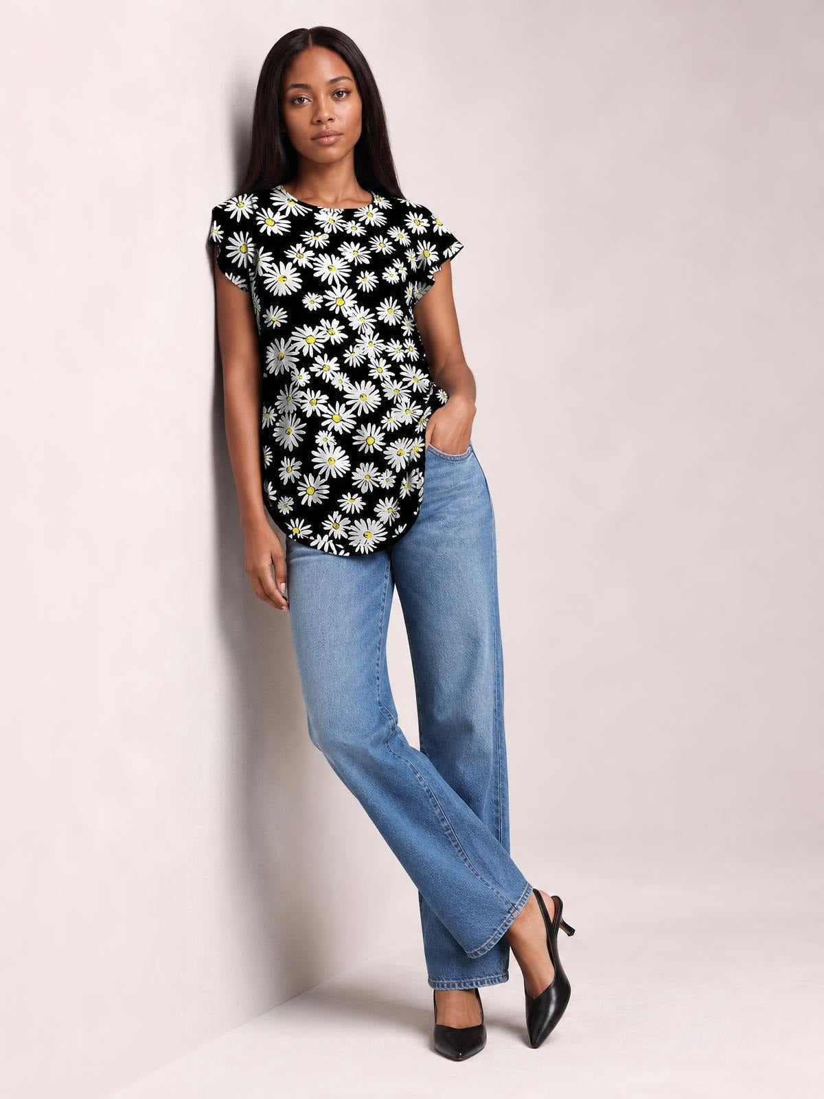 Model wears a black floral-print round-neck short-sleeve T-shirt with a relaxed silhouette and curved hem, posing with one hand in her jeans pocket.