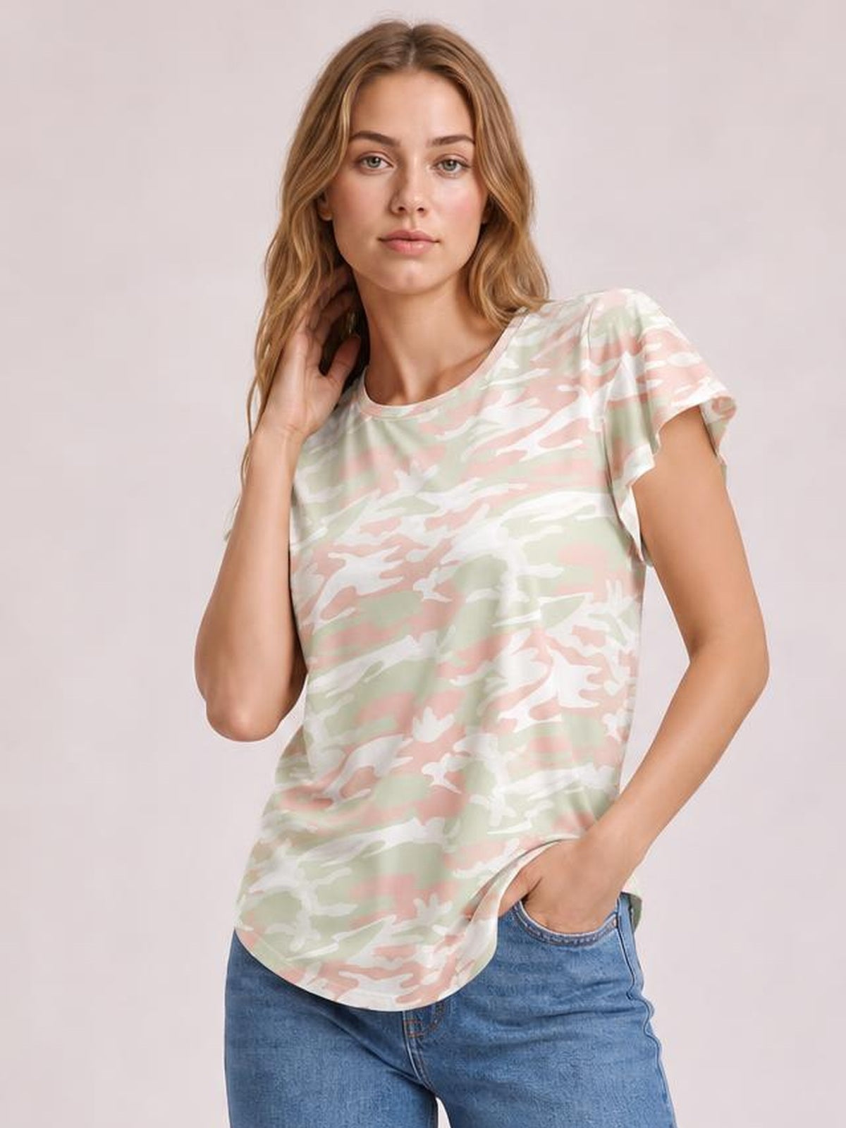 Model poses in a pastel camouflage printed round neck short sleeve T-shirt with a relaxed silhouette, curved hem, and slight stretch.