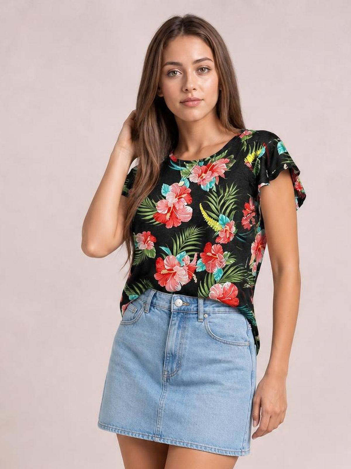 Model poses in a black printed round neck short sleeve T-shirt with colorful floral and leafy motifs, a relaxed silhouette, and slightly ruffled sleeves.