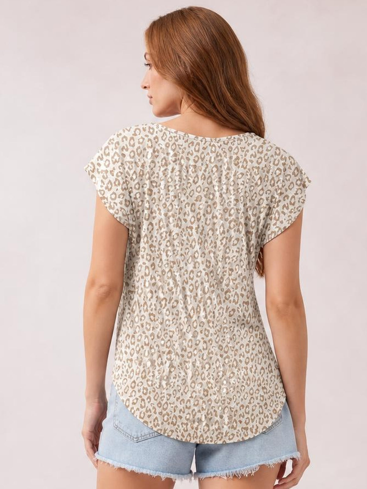 Model shown from behind wearing an opaque ivory printed round-neck short-sleeve T-shirt with a relaxed silhouette, leopard-style pattern, and curved hem.