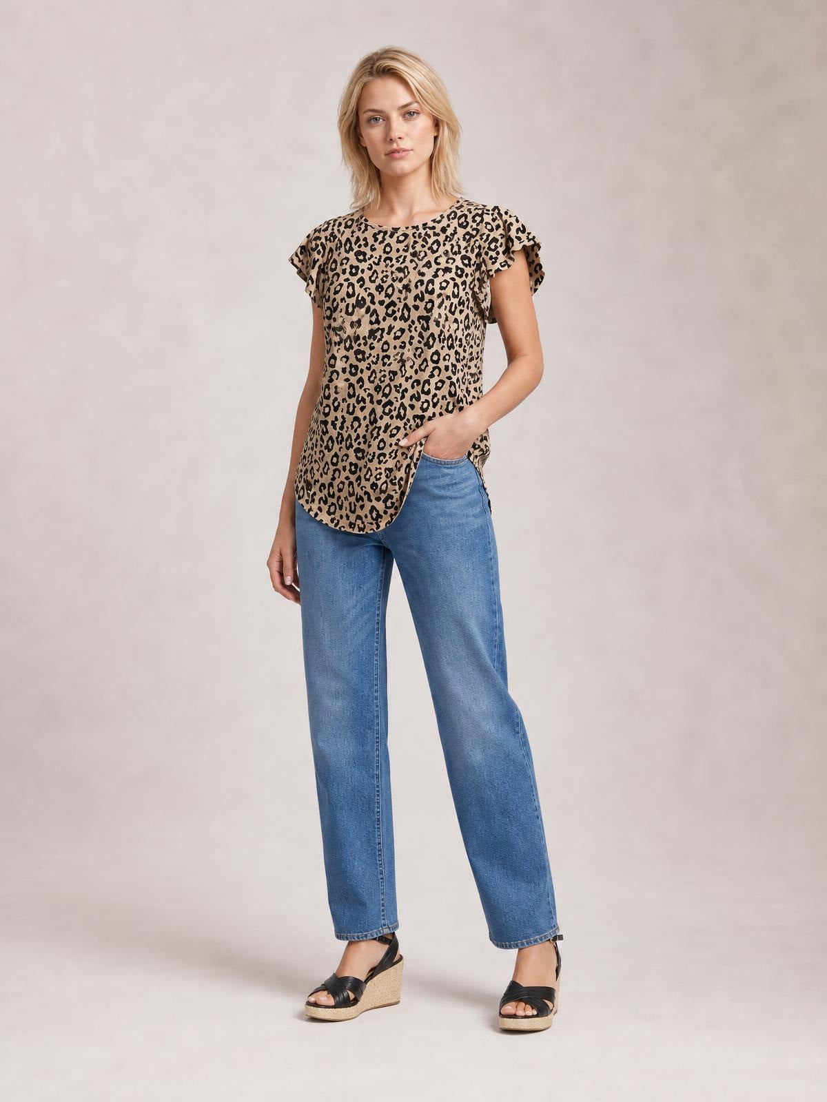 Model poses in a leopard-print round-neck T-shirt with short flutter sleeves, a relaxed silhouette, and a curved hem, paired with jeans.