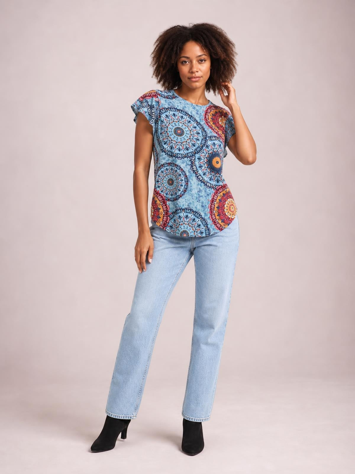 Model wearing a blue printed round neck short sleeve T-shirt with a relaxed straight silhouette, standing with one hand touching her hair.
