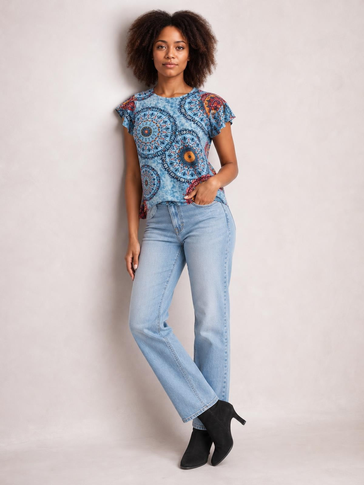 Model poses in a blue printed round neck short sleeve T-shirt with a relaxed straight silhouette and slightly ruffled sleeve edges.