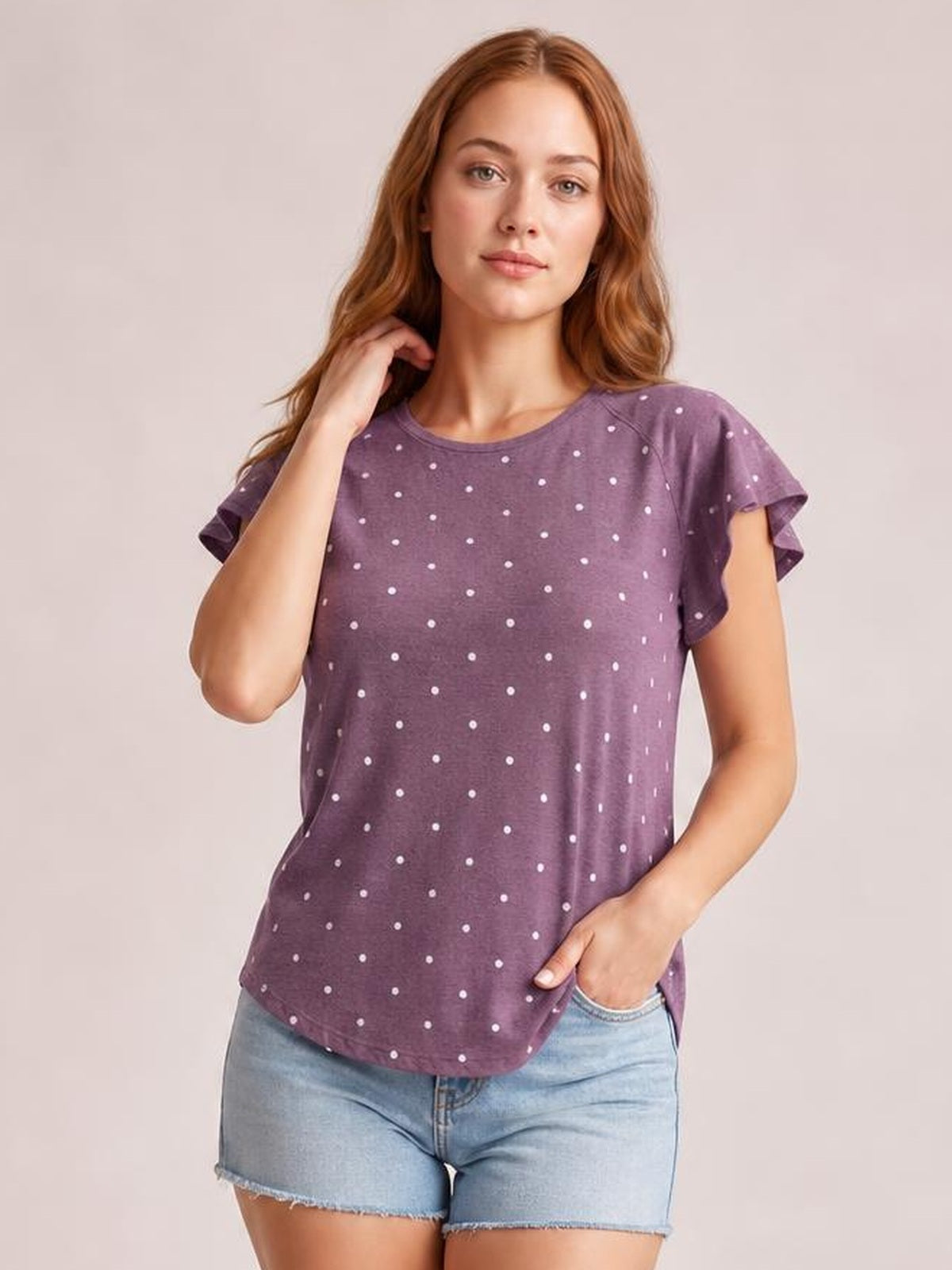 Model poses in a purple round neck short sleeve T-shirt with a white dotted print, relaxed silhouette, and slightly curved hem.
