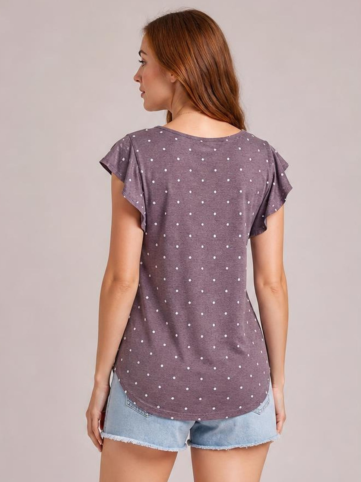 Model shown from the back wearing a mauve printed round neck short sleeve T-shirt with white polka dots and a relaxed, curved-hem silhouette.