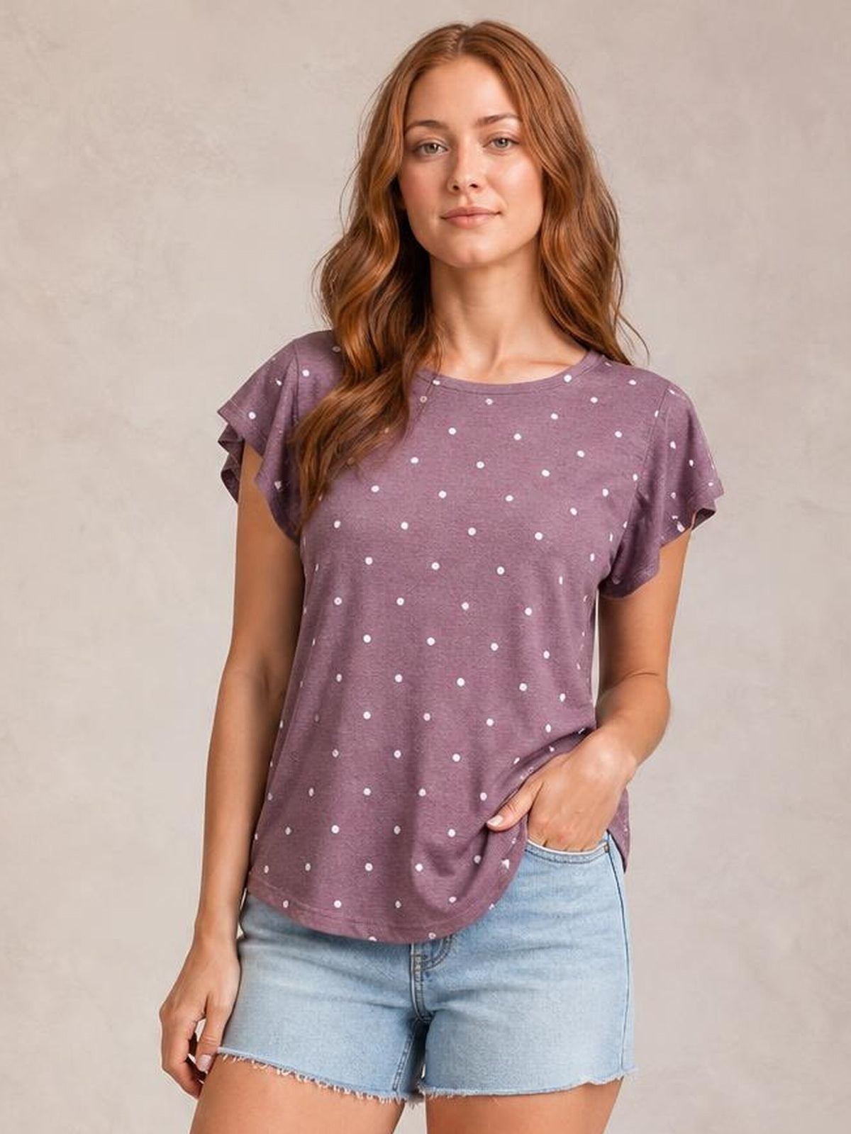 Model wearing a mauve printed round neck short sleeve T-shirt with a relaxed silhouette, layered flutter sleeves, and white polka dots.
