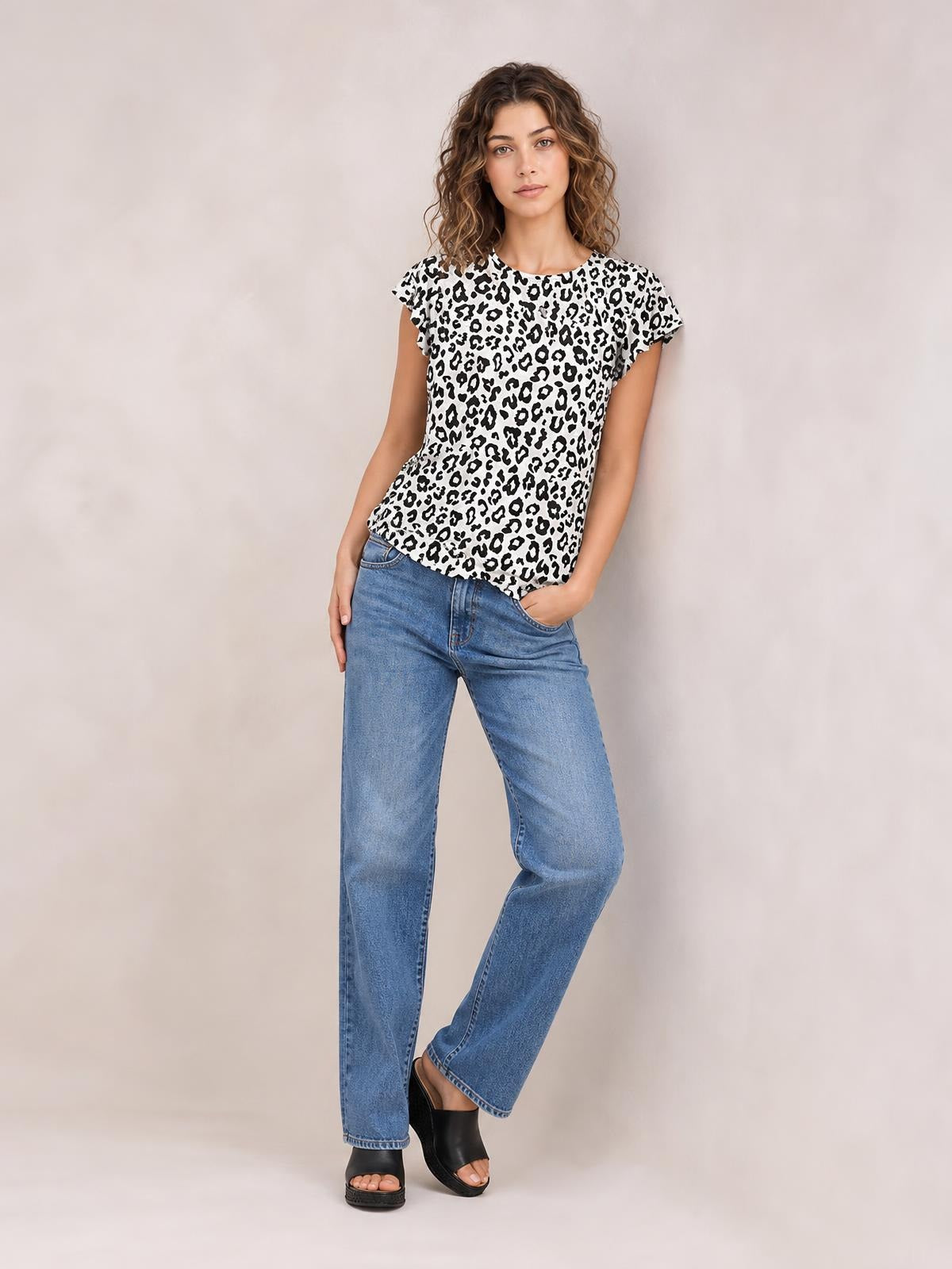 A model poses in a black-and-white leopard print T-shirt with a round neck, short sleeves, and a relaxed silhouette, paired with jeans.