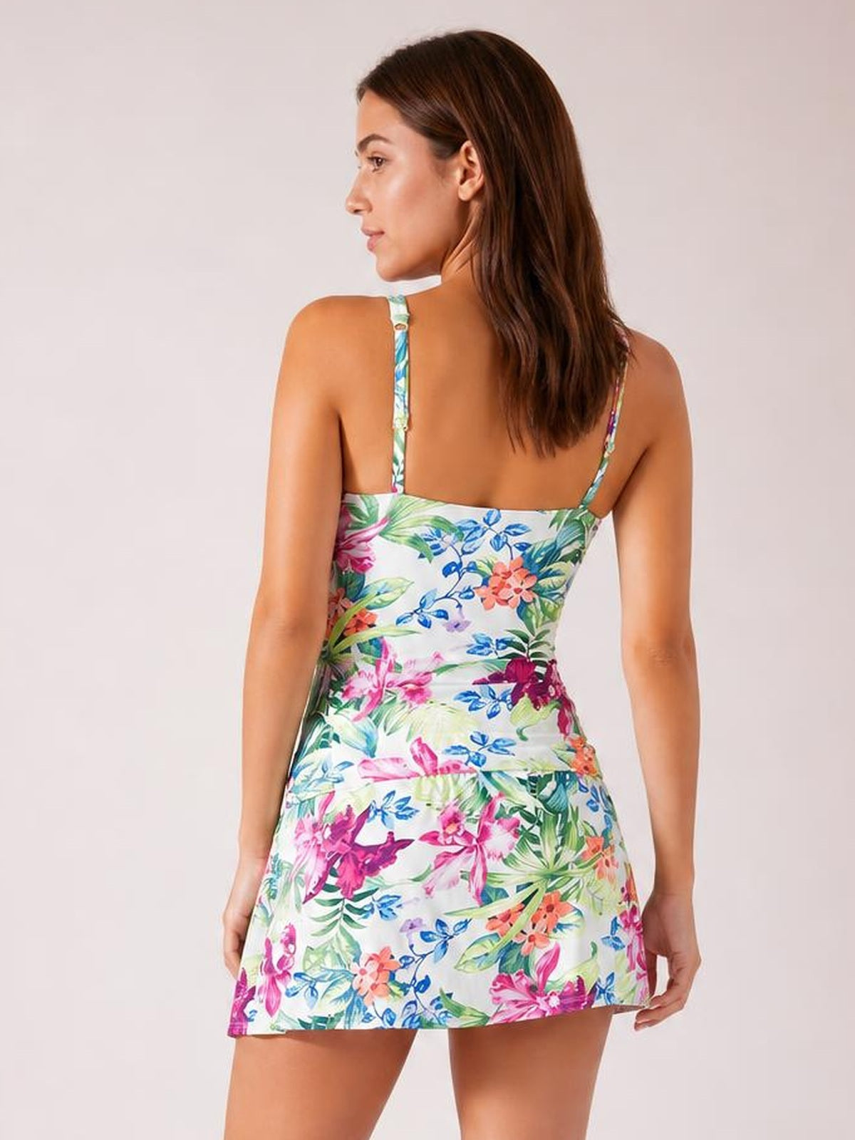 Model viewed from behind in a colorful floral printed tankini with spaghetti straps, a fitted bodice, and flared swim skirt silhouette.