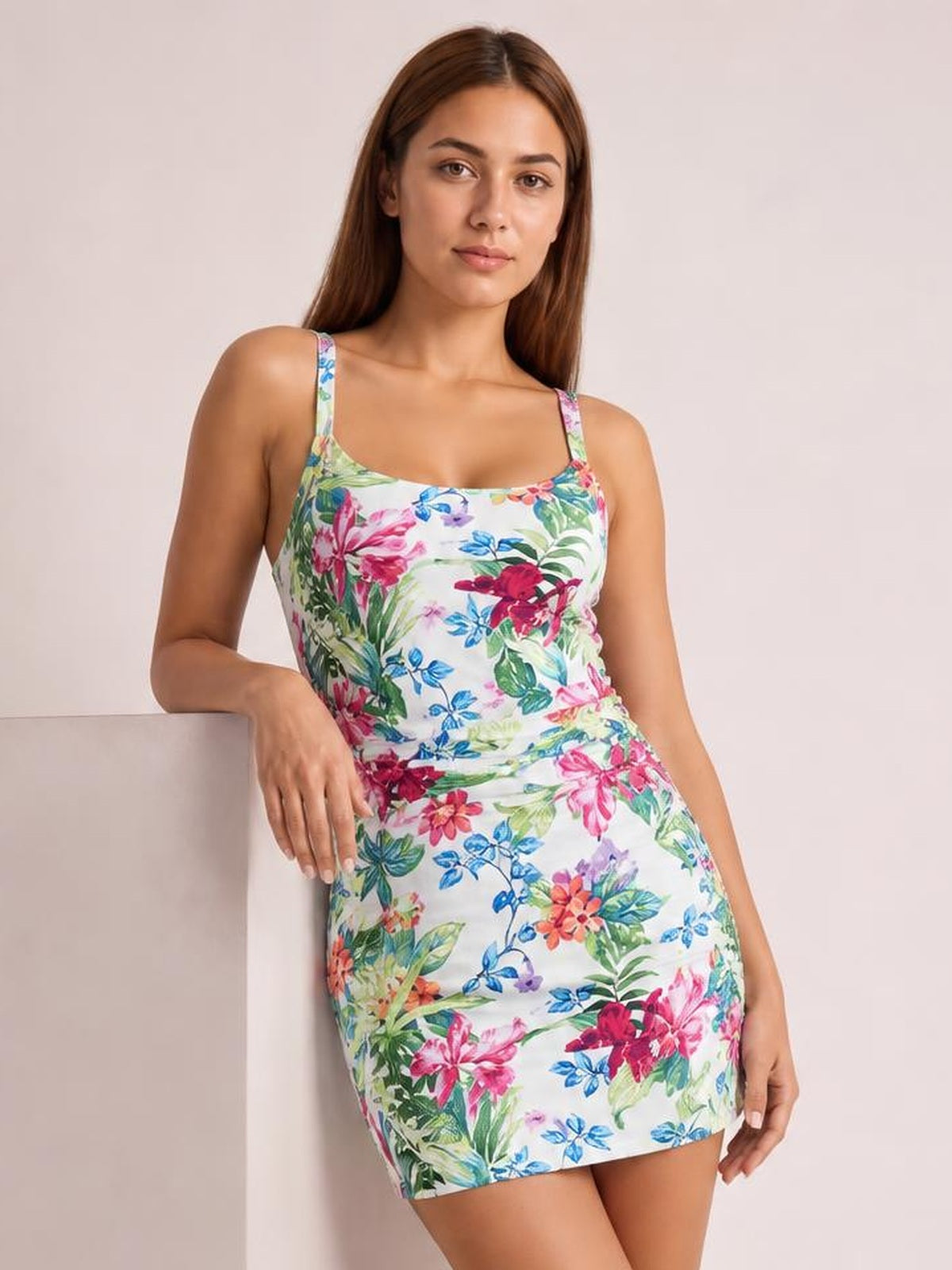 Model poses in a floral printed tankini swim set with spaghetti straps, a fitted white top, and matching short skirt silhouette.