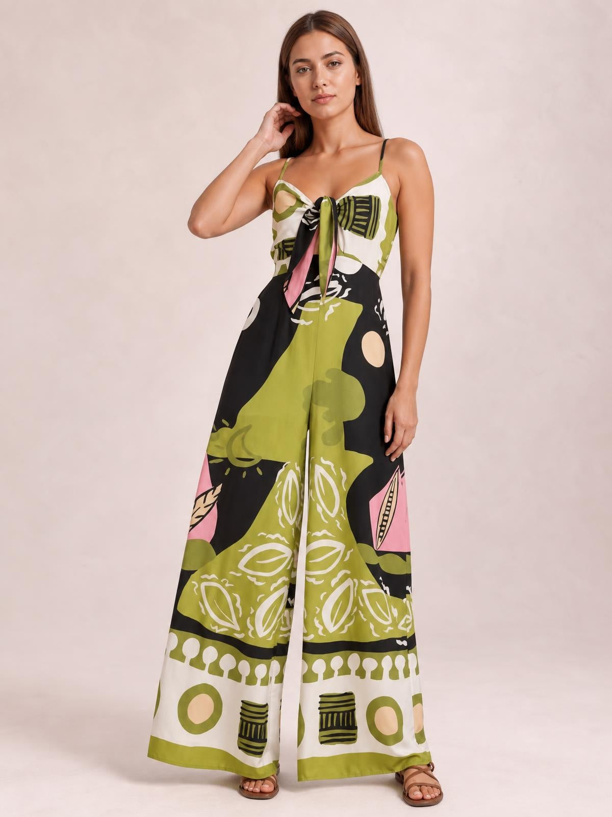 Model poses in a multicolor printed sweetheart-neck jumpsuit with spaghetti straps, a tied front, and a flowing wide-leg silhouette.