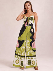 Model poses in a multicolor printed sweetheart-neck jumpsuit with spaghetti straps, a tied front, and a flowing wide-leg silhouette.
