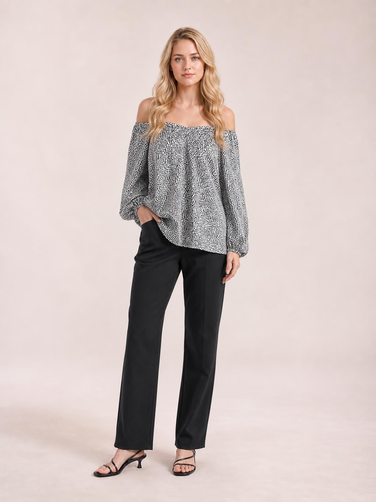 Model poses in a black-and-white printed blouse with a wide neckline, long balloon sleeves, and a relaxed flowing silhouette.