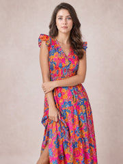 A model poses with folded arms in a vivid floral V-neck midi dress featuring flutter cap sleeves, a defined waist, and a softly tiered skirt.