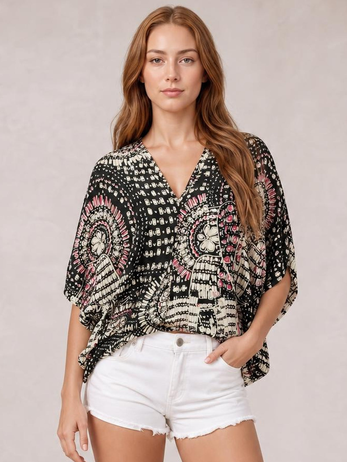 Model wearing a black printed V-neck half-sleeve top with a loose silhouette, draped hem, and bold white and pink pattern.