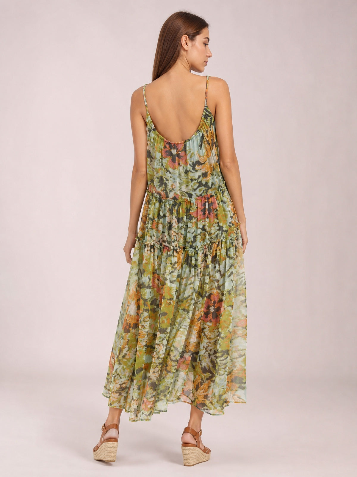 Model shown from the back in a floral printed sleeveless dress with thin straps, gathered waist, tiered ankle-grazing skirt, and flowing silhouette.