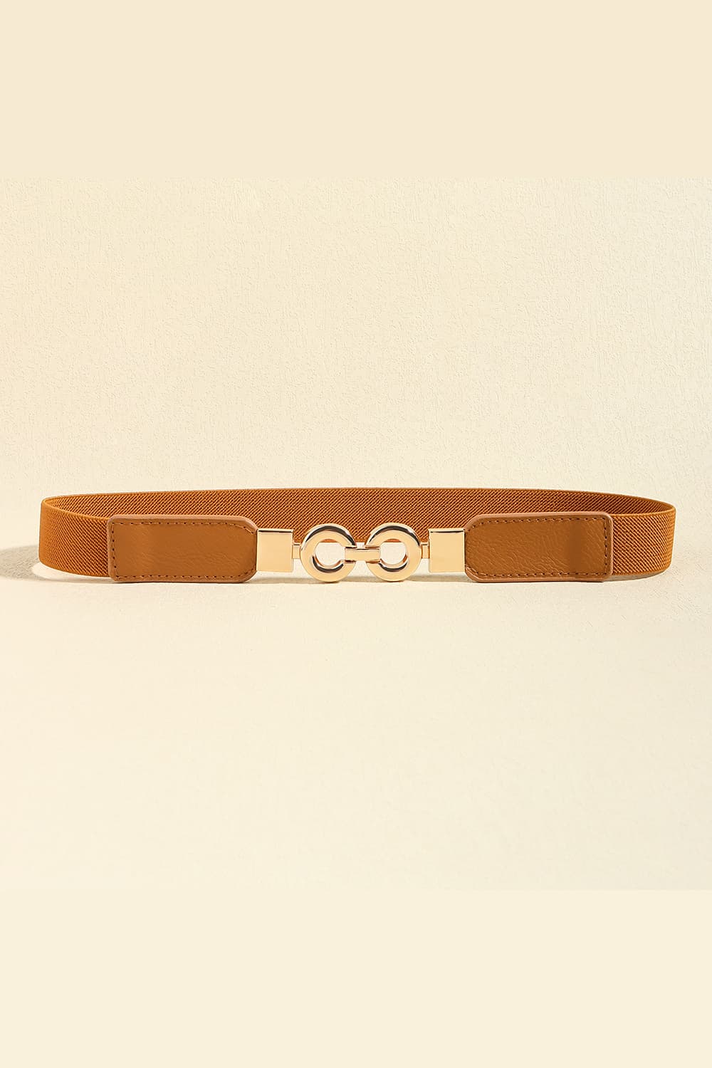 A brown PU leather belt features a slim structured silhouette, stitched leather panels, and a polished alloy buckle with two linked circular elements.