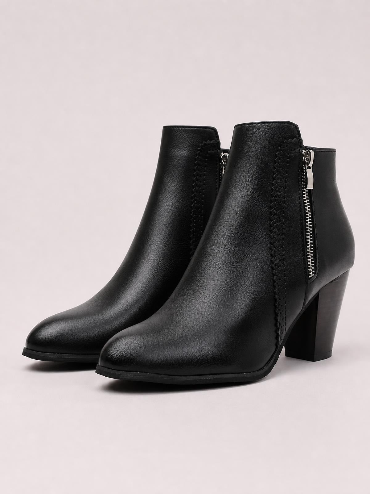 Black PU leather ankle boots feature rounded toes, high block heels, side zippers, and stitched panels for a structured silhouette.