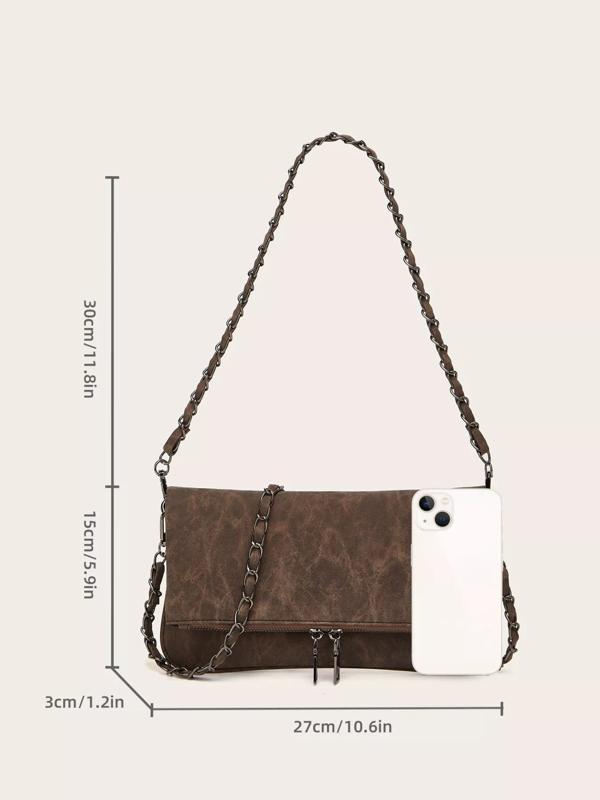 Medium brown PU leather shoulder bag with a rectangular silhouette, woven chain strap, flap closure, and front zip pocket, shown beside a smartphone for scale.
